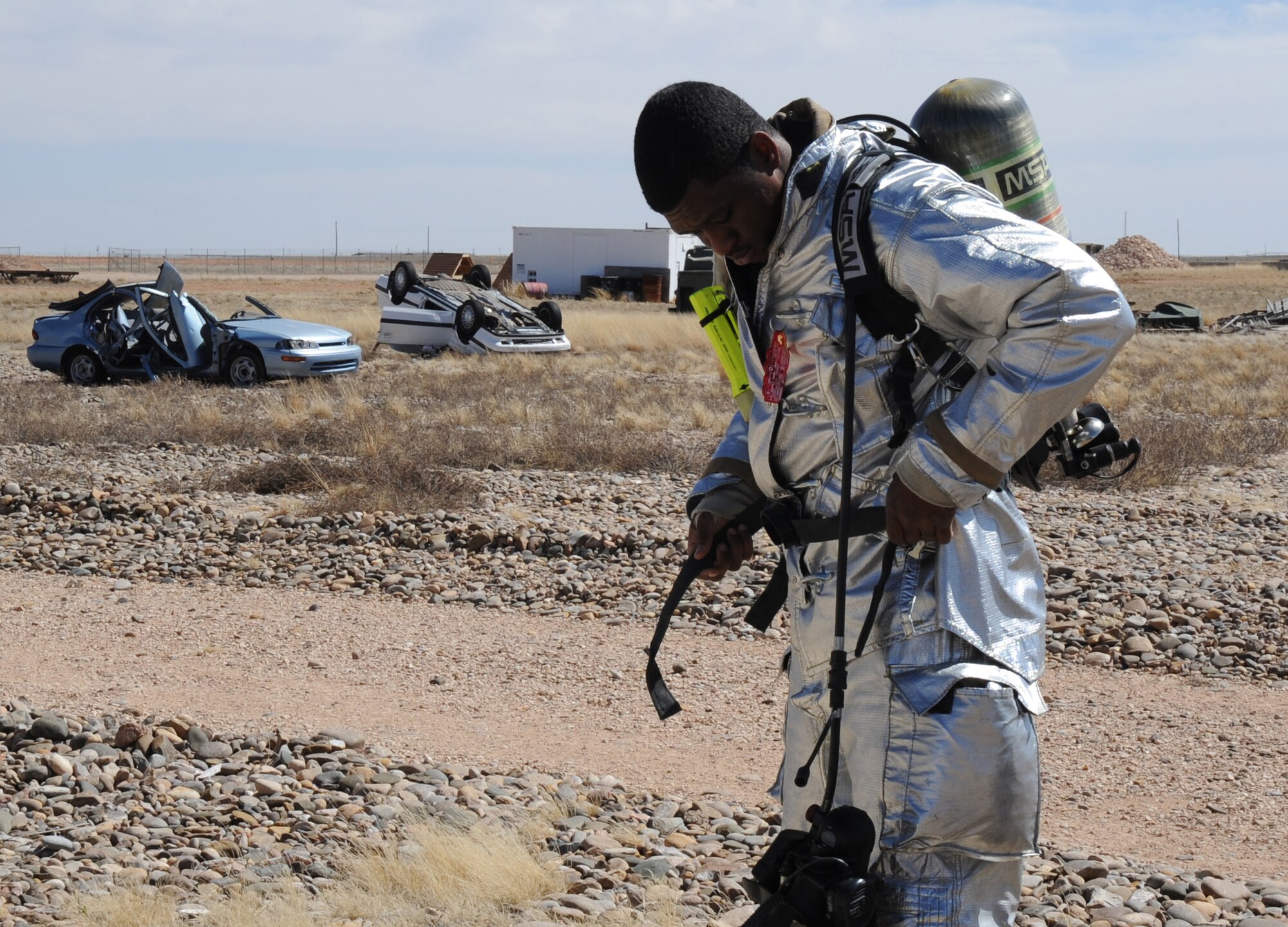 A U.S. Air Force firefighter with the 27th Special Operations Civil Engineer Squadron secures his fire-resistant gear during a controlled burn at Cannon Air Force Base, N.M., March 15, 2012. Firefighting crews routinely perform exercises like this controlled burn to ensure readiness during an actual disaster. (U.S. Air Force photo by Airman 1st Class Alexxis Pons Abascal)