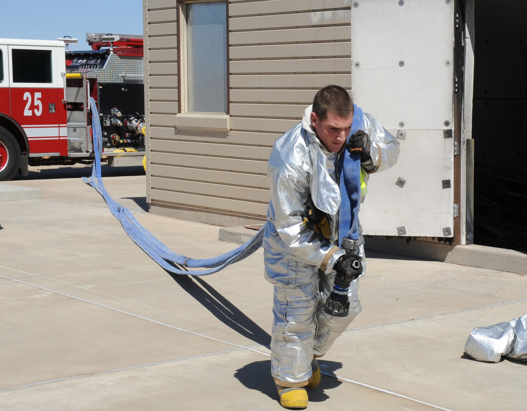 A U.S. Air Force firefighter with the 27th Special Operations Civil Engineer Squadron unravels a hose from a nearby fire engine during a controlled burn at Cannon Air Force Base, N.M., March 15, 2012. Firefighting crews routinely perform exercises like this controlled burn to ensure readiness during an actual disaster. (U.S. Air Force photo by Airman 1st Class Alexxis Pons Abascal) 