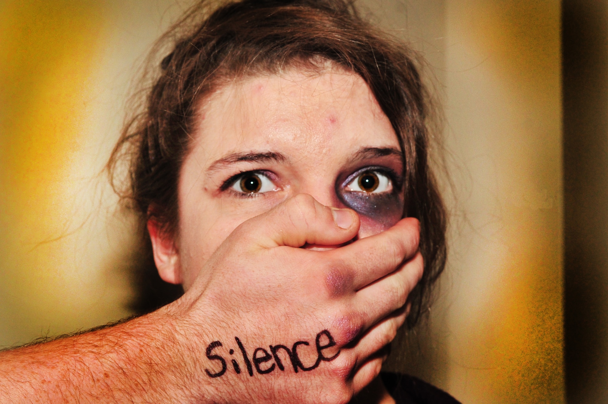 U.S. Air Force Airman Jodi Lange, 20th Medical Support Squadron, poses for an illustration photo depicting an abused woman silenced by her abuser as a result of sexual assault, Shaw Air Force Base, S.C. March 25, 2012. Studies show that men, women and children of all ages, races, religions, and economic classes can be and have been victims of sexual assault. (U.S. Air Force photo illustration by Airman 1st Class Ashley L. Gardner/ Released)