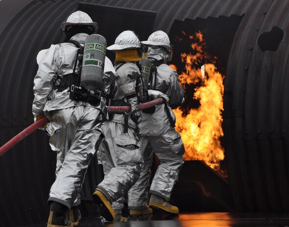 Beale firemen head towards aircraft interior fire during a live fire exercise at Beale Air Force Base, Calif., March 19, 2012. The simulated aircraft is capable of producing different fire scenarios from cockpit fires to cargo bay fires. (U.S. Air Force photo by Staff Sgt. Robert M. Trujillo/Released) 