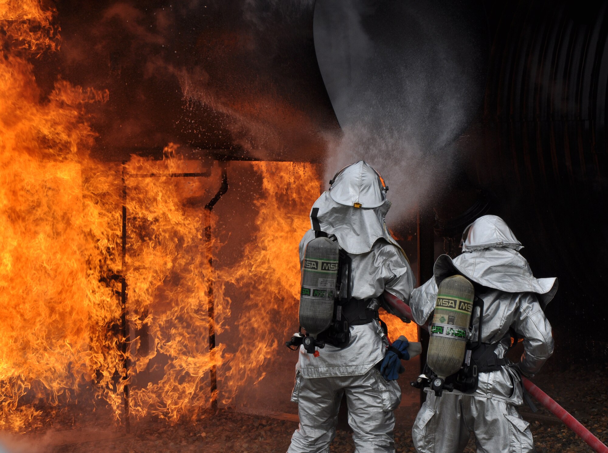 Beale firefighters, Airman 1st Class Sean Russell and Staff Sgt. Nathan Shaw battle an aircraft fire on a simulated aircraft at Beale Air Force Base, Calif., March 19, 2012. Beale firefighters routinely train at the aircraft simulation pit to enhance their skills and showcase their abilities to fire department leadership. (U.S. Air Force photo by Staff Sgt. Robert M. Trujillo/Released)