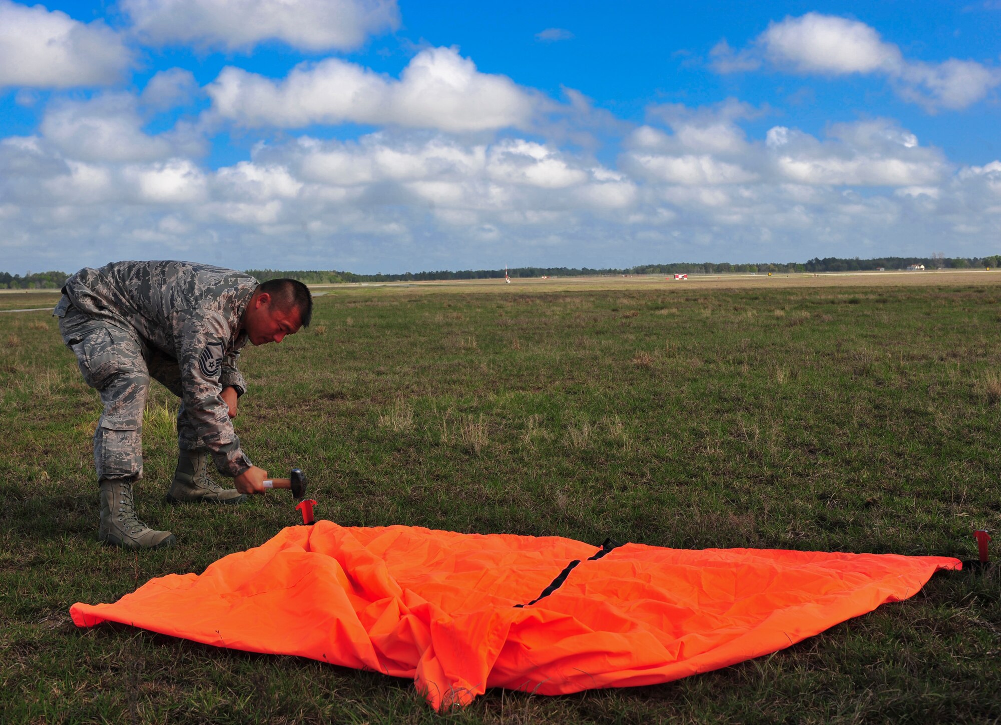 U.S. Air Force Master Sgt. Samuel Louie, 820th Combat Operations Squadron, hammers a stake into the ground to secure the raised angle marker at Moody Air Force Base, Ga., March 21, 2012. The raised angle marker is the point of impact where the first jumper should land. (U.S. Air force photos by Staff Sgt. Stephanie Mancha/Released)
