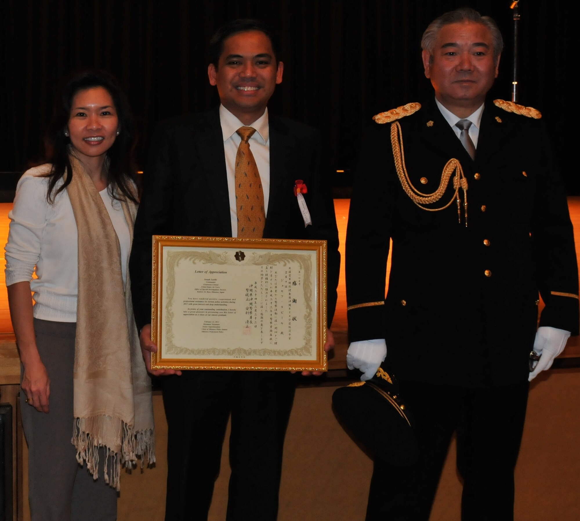 Special Agent Joseph Laville (center), U.S. Air Force Office of Special Investigations Detachment 624, with his wife Violet, receives a letter of appreciation from Kiyomasa Yasumura (right), Chief of the Okinawa Police Station, at the Okinawa Police Station's annual appreciation ceremony in Okinawa City, Japan, February 22, 2012. The letter of appreciation was for assisting in various police activities on Okinawa during 2011. (U.S. Air Force courtesy photo/Released)