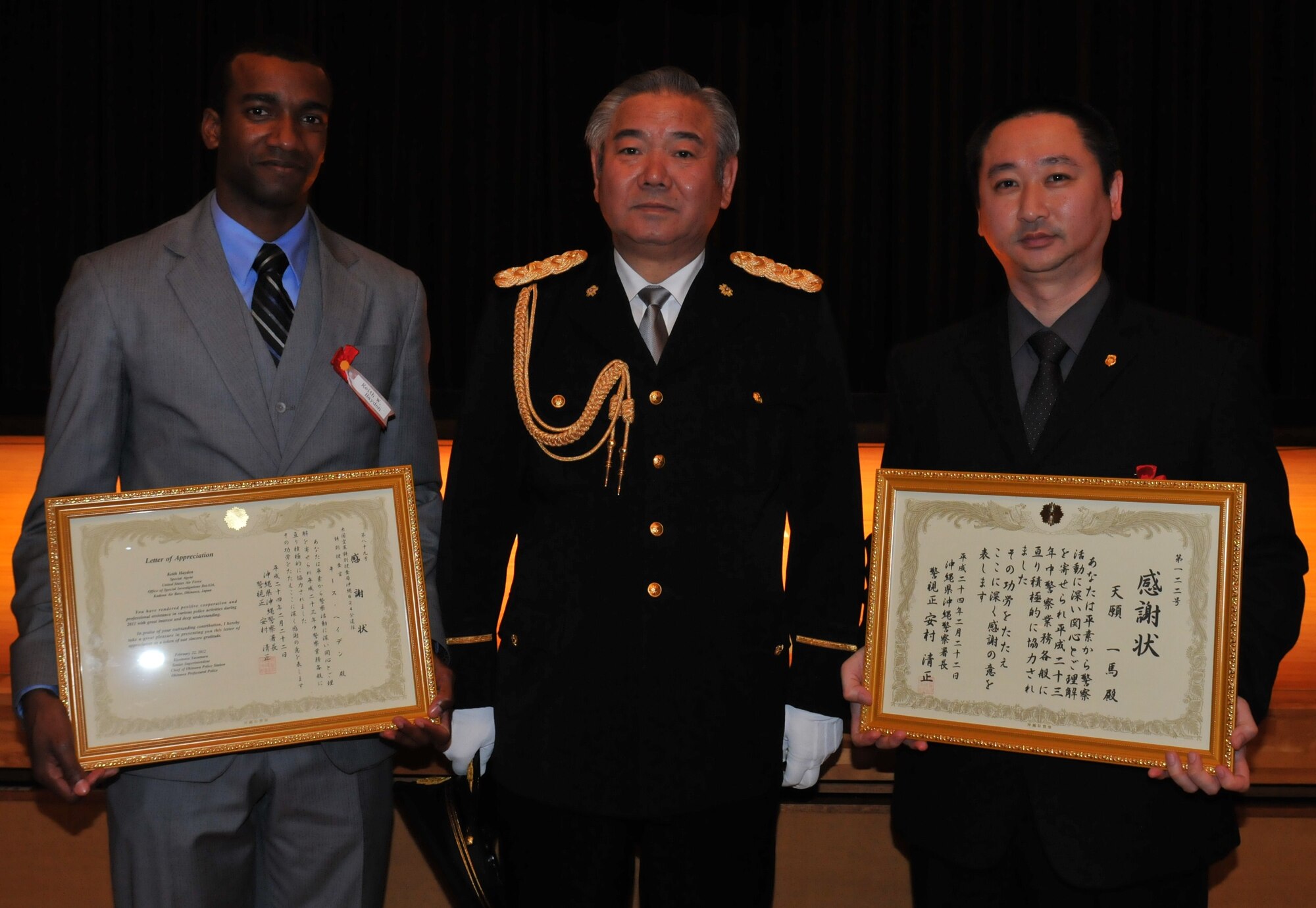 Special Agent Keith Hayden (left) and Special Investigator Kazuma Tengan (right), U.S. Air Force Office of Special Investigations Detachment 624, receive a letter of appreciation from Kiyomasa Yasumura (center), Chief of the Okinawa Police Station, at the Okinawa Police Station's annual appreciation ceremony in Okinawa City, Japan, February 22, 2012. The letter of appreciation was for assisting in various police activities on Okinawa during 2011. (U.S. Air Force courtesy photo/Released)