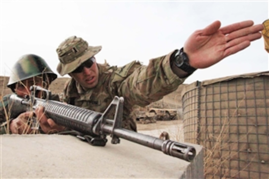 U.S. Army 1st Lt. Spencer Tadken (right) reviews aiming techniques with an Afghan soldier during training at Forward Operating Base Shank, in Logar province, Afghanistan, on March 13, 2012.  Tadken is with the 1st Armored Division's 3rd Infantry Brigade Combat Team.  
