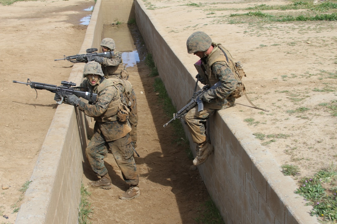Recruits of Company K, 3rd Recruit Training Battalion, jump into a trench and provide cover before moving on in Copeland's Assault at the Crucible aboard Edson Range, Camp Pendleton, Calif., March 28. Copeland's Assault is a simulated combat course that has recruits climb through tunnels, crawl under barbed wire, and more in order to complete their mission.