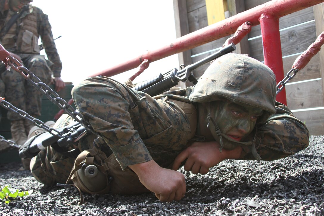 Recruit Dillon Pickard, Platoon 3221, Company K, 3rd Recruit Training Battalion, lays across a chain bridge to assist his fellow recruits to the other side at 12-Stall aboard Edson Range, Weapons and Field Training Battalion, Camp Pendleton, Calif. March 28. 12-Stall challenges recruits with various obstacles they must utilize teamwork in order to complete.