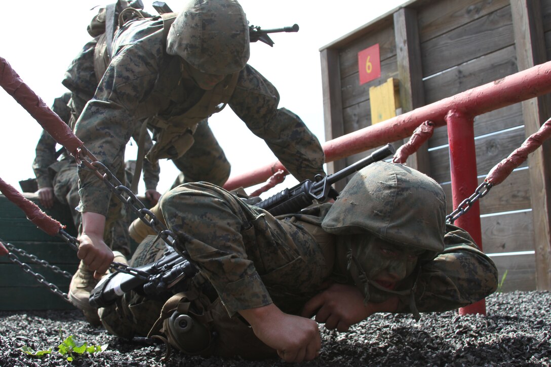 Recruit Dillon Pickard, Platoon 3221, Company K, 3rd Recruit Training Battalion, lays across a chain bridge to assist his fellow recruits to the other side at 12-Stall at the Crucible aboard Edson Range, Camp Pendleton, Calif., March 28. 12-Stall challenges recruits with various obstacles they must utilize teamwork in order to complete.