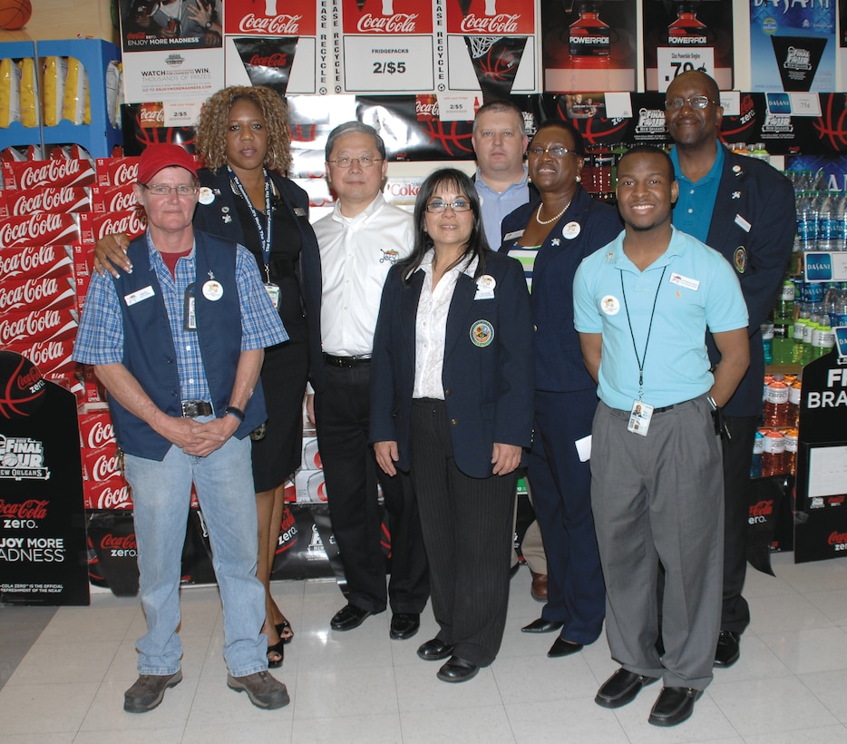 Joseph H. Jeu, center, poses with Cynthia Blair, left, store director, Commissary, and her employees after touring the store, March 22. He thanked the employees for their hard work and recognized several employees for their distinguished service by giving them a DECA?coin.