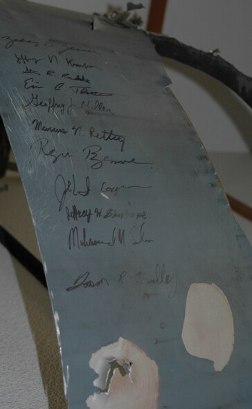 A C-5 Galaxy engine cover, on display in the 22nd Airlift Squadron building at Travis Air Force Base, Calif., March 28, 2012, is signed by the 11 crewmembers on board Jan. 8, 2004, when the aircraft was hit with a surface-to-air missile strike. The engine cowling, or cover, has been on display since 2004 and serves as a reminder of the training, preparedness and resolve the squadron faced during that mission. (U.S. Air Force photo/Tyler Grimes)