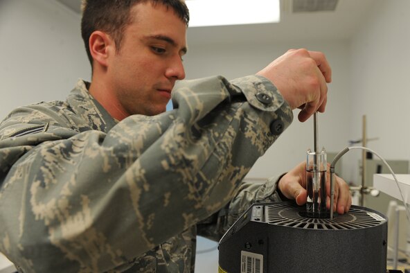 U.S. Air Force Senior Airman Michael Agliardo lowers a vial of water into a dry well in the precision measurement equipment laboratory on Seymour Johnson Air Force Base, N.C., March 28, 2012. After a set time Agliardo removes the vial, then uses the three forms of matter created in the vial to act as a reference point for temperature measurements. Agliardo, 4th Component Maintenance Squadron test measurement diagnostic equipment technician, is from Emporium, Pa. (U.S. Air Force photo/Airman 1st Class John Nieves Camacho/Released)