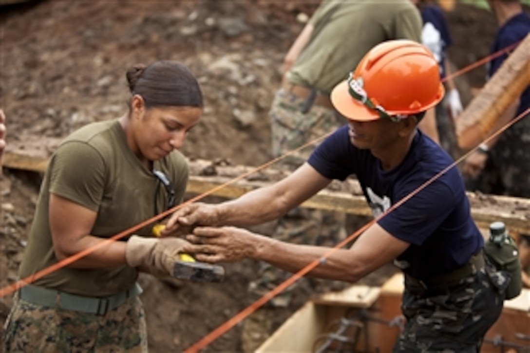 U.S. Marine Corps Lance Cpl. Melinda Carbajal (left) with Marine Wing Support Squadron 172, 1st Marine Aircraft Wing, and Philippine Navy Petty Officer 2nd Class Alfredo Mendoza exchange tools at a construction site at Santa Cruz Elementary School, Palawan province, Philippines, on March 22, 2012.  Philippine navy Seabees partnered with U.S. Marines to construct a building for the school as part of a humanitarian and civic assistance project for exercise Balikatan 2012.  Balikatan is an annual bilateral training exercise designed to increase interoperability between the Armed Forces of the Philippines and the U.S. military when responding to future natural disasters.  