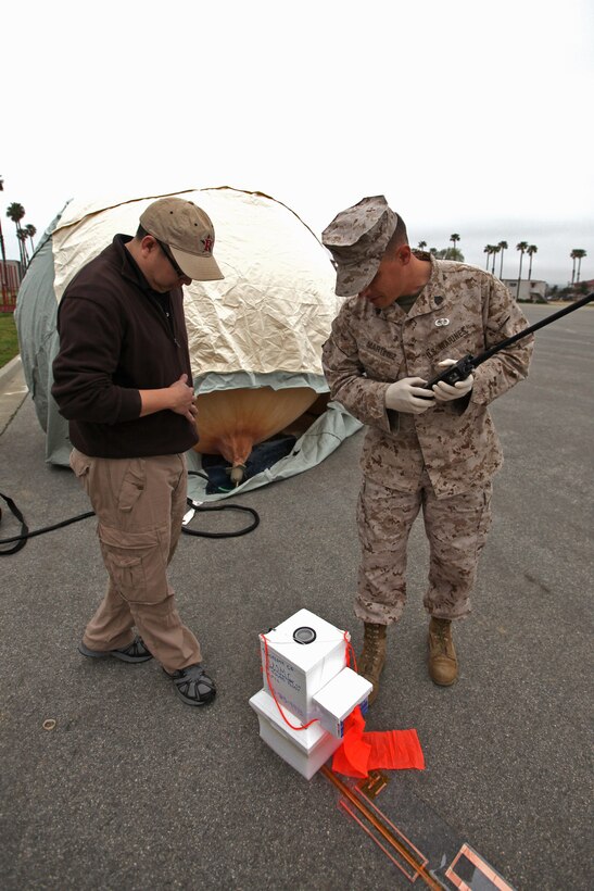 Pyisone Win, project manager, Space Data Corporation, and Sgt. Emmanuel T. Martinez, radio supervisor, Command Element, 15th Marine Expeditionary Unit, prepare the Combat SkySat communication system at Camp Pendleton, Calif., March 29, before allowing the helium balloon to float to Earth’s stratosphere. The SkySat system is used to retransmit UHF signals to increases the range of communication up to 600 miles in diameter and expands the capabilities of the Marine Air Ground Task Force.::r::::n:: ::r::::n::