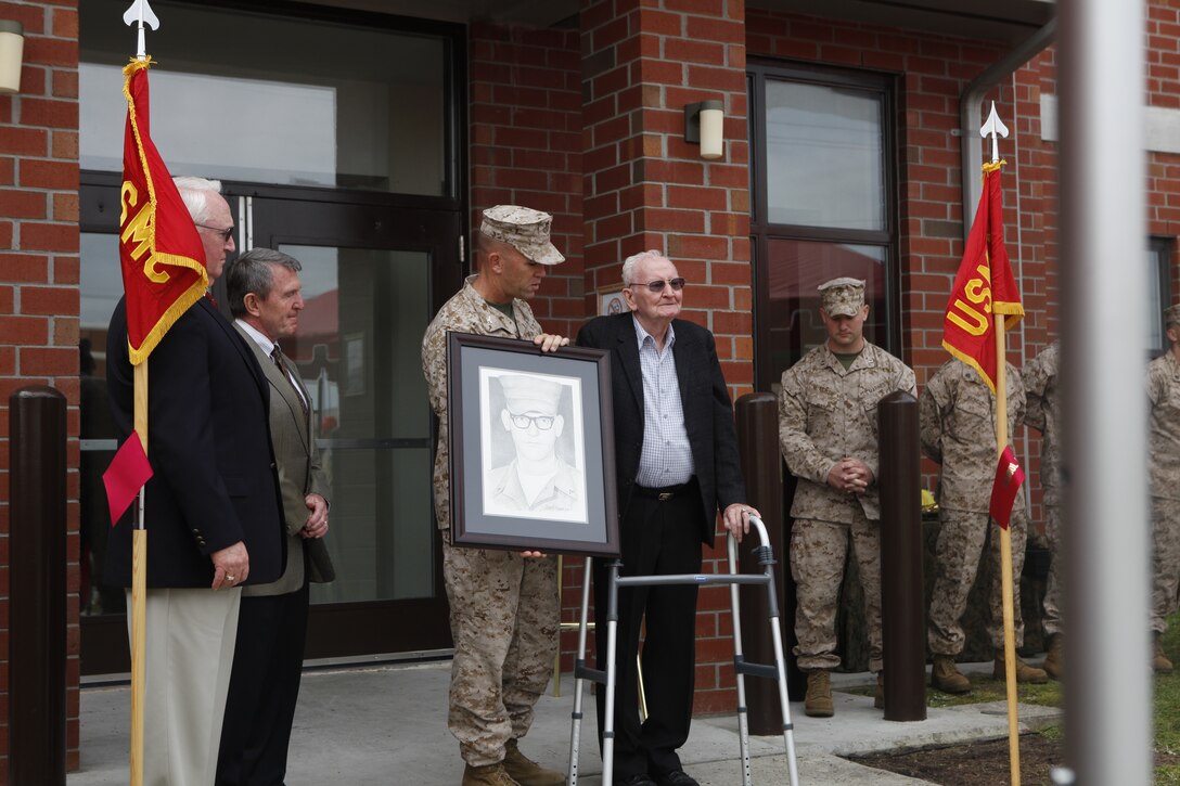 Col. Barry J. Fitzpatrick, commanding officer of School of Infantry – East, hands a portrait of Cpl. John “Jack” Loweranitis, a time honored Marine who lost his life in the Battle of Getlin’s Corner, to a family member during a barracks dedication ceremony, March 30.