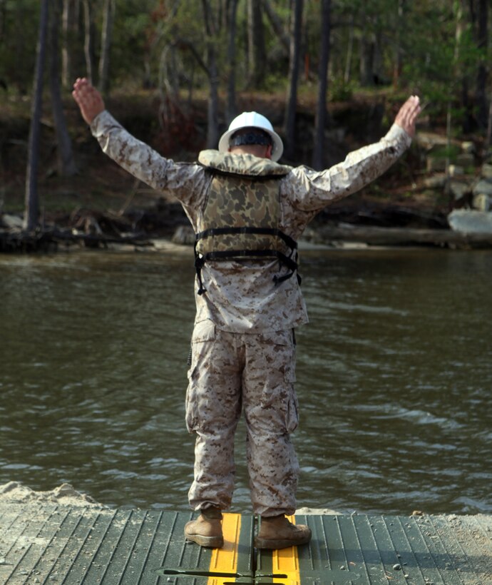 Cpl. Eric Maynard, a combat engineer with 8th Engineer Support Battalion, 2nd Marine Logistics Group, directs the drivers of the MKIII Bridge Erection Boat to prepare the raft for landfall during an operation aboard Camp Lejeune, N.C., March 30, 2012.  The Marines of Bridge Company, 8th ESB used the raft to transport 15 vehicles across the New River to ensure the Marines of 2nd Tank Battalion, 2nd Marine Division could complete their mission.