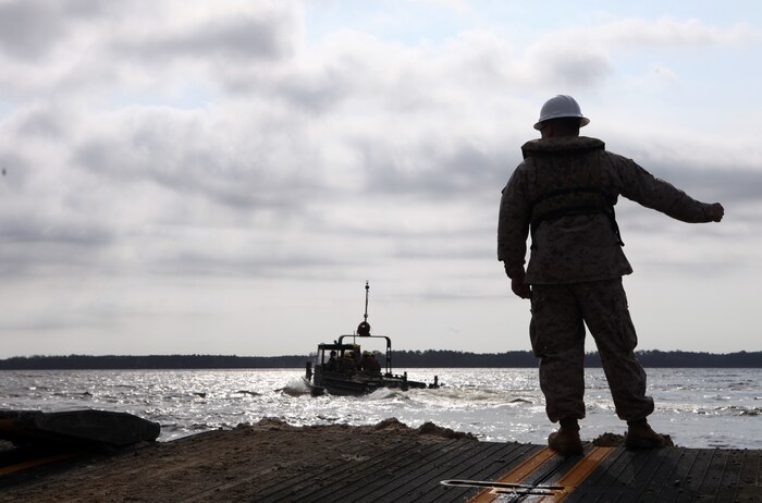 Cpl. Eric Maynard, a combat engineer with 8th Engineer Support Battalion, 2nd Marine Logistics Group, directs the drivers of the MKIII Bridge Erection Boats, which pushes the raft across the river, aboard Camp Lejeune, N.C., March 30, 2012.  The Marines of Bridge Company, 8th ESB used the raft to transport 15 vehicles across the New River to ensure the Marines of 2nd Tank Battalion, 2nd Marine Division could complete their mission.