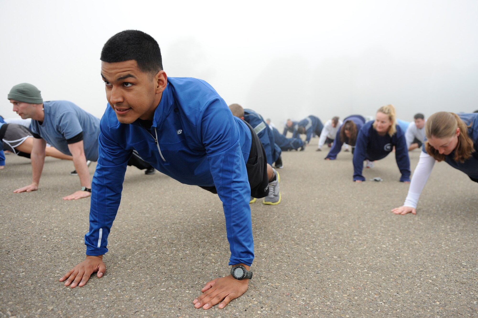 VANDENBERG AIR FORCE BASE, Calif. -- Senior Airman Johnathan Rubio, a 30th Security Forces Squadron visitor center technician, performs push-ups to warm up prior to the monthly Fit-to-Fight Run here Friday, March 20, 2012. Runners were encouraged to wear blue and teal T-shirts, representing Child Abuse Awareness Month and Sexual Assault Awareness Month respectively. Various events will be held for both causes throughout the month, contact the sexual assault response coordinator and family advocacy office for more details. (U.S. Air Force photo/Staff Sgt. Levi Riendeau)