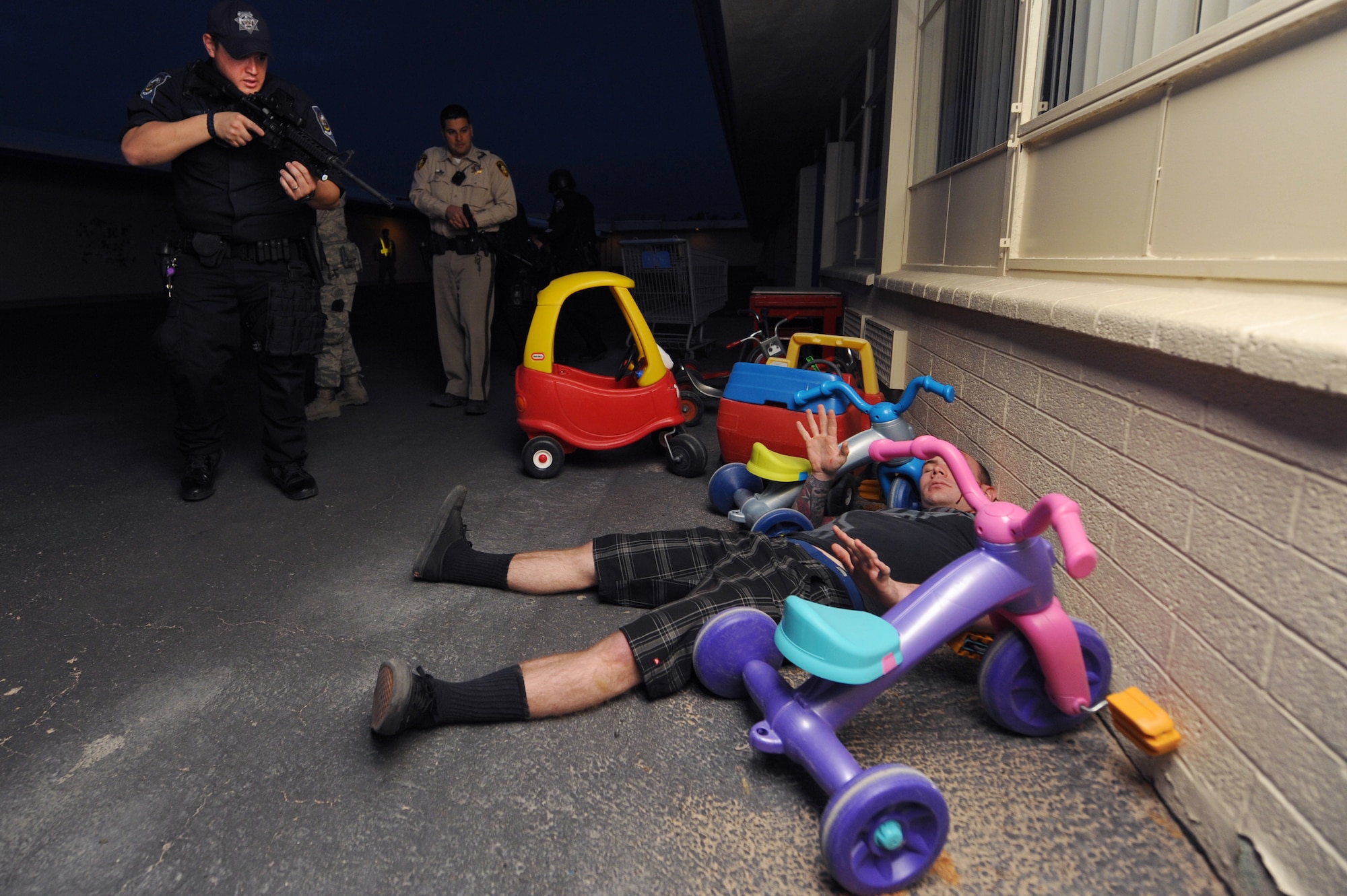 A law enforcement team consisting of two North Las Vegas Police Department police officers, one Airman from the 99th Security Forces Squadron, one Nevada Highway Patrol officer and one Las Vegas Metro Police Department officer find a simulated casualty at Lomie Heard Elementary School, March 28, 2012, during a  Multi Assault Counter Terrorism Action Capabilities exercise at Nellis Air Force Base, Nev. After finding the injured person, the team had to escort the victim to a medic while on the look out for two gunmen. (U.S. Air Force photo by Staff Sgt. William P.Coleman)
  

