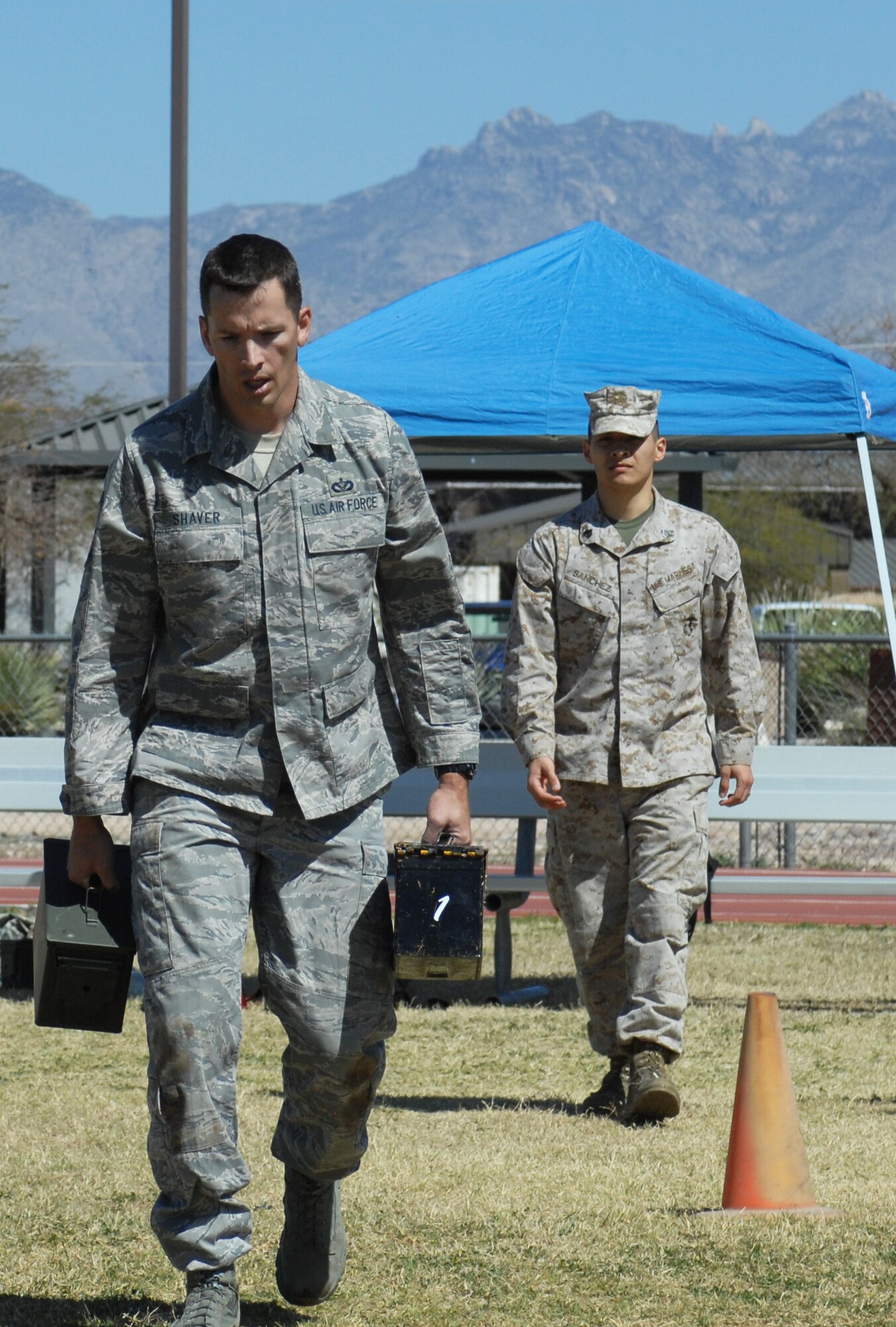 U.S. Air Force Master Sgt. Kevin Shaver, 355th Civil Engineer Squadron, carries two pound boxes of ammunition down the obstacle course portion of the Marine Challenge held at Benko Fitness Center track on Davis-Monthan Air Force Base, Ariz., March 23. Shaver was part of the second group of participants to complete the challenge. (U.S. Air Force photo by Airman 1st Class Saphfire Cook/Released)