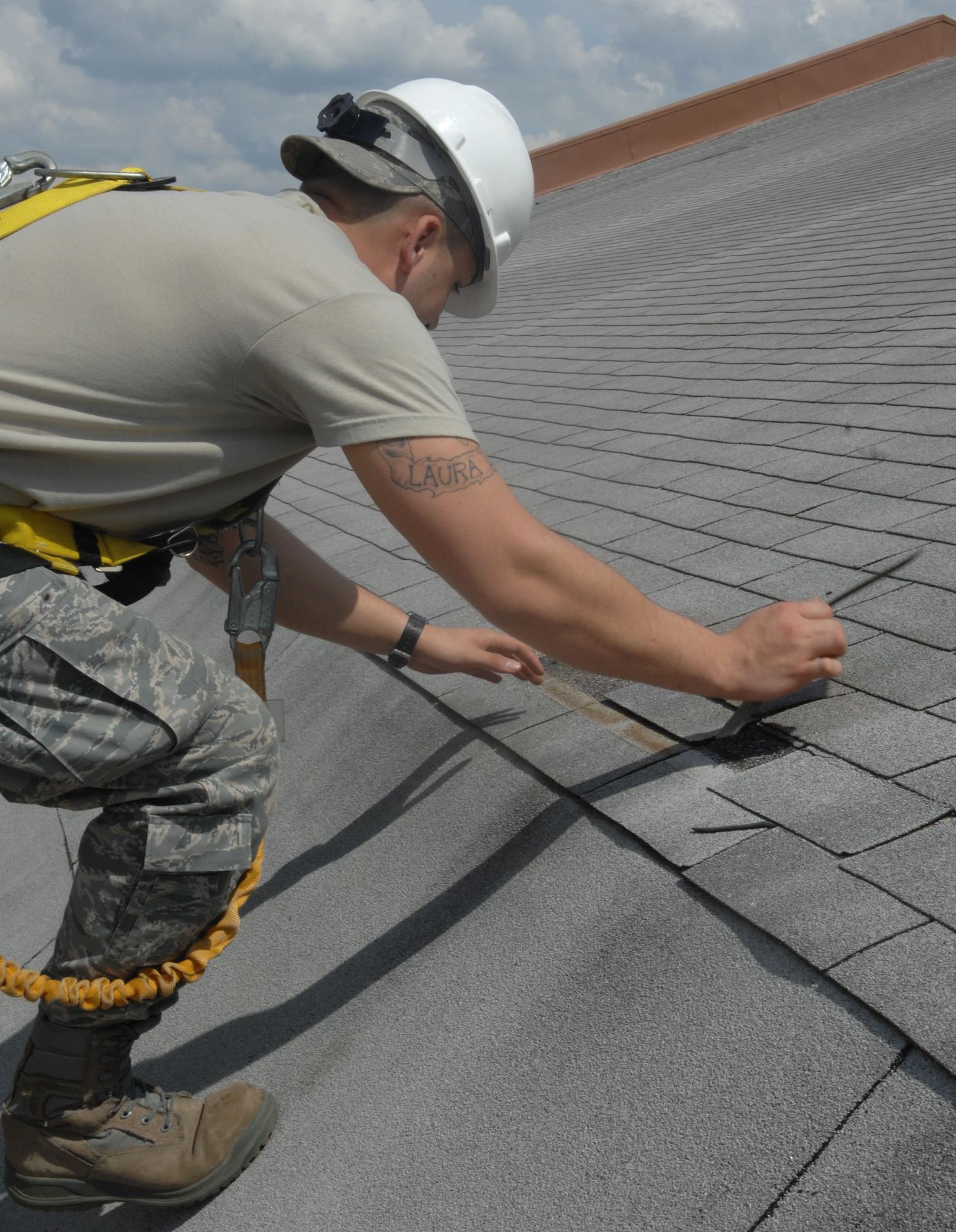 Senior Airman Steven Price, 2nd Civil Engineer Squadron structural apprentice, places fallen shingles back in place on the roof of the 20th Bomb Squadron on Barksdale Air Force Base, La., March 28. Price often performs maintenance on the roofs at Barksdale. (U.S. Air Force photo/Airman 1st Class Joseph A. Pagán Jr.)(RELEASED)