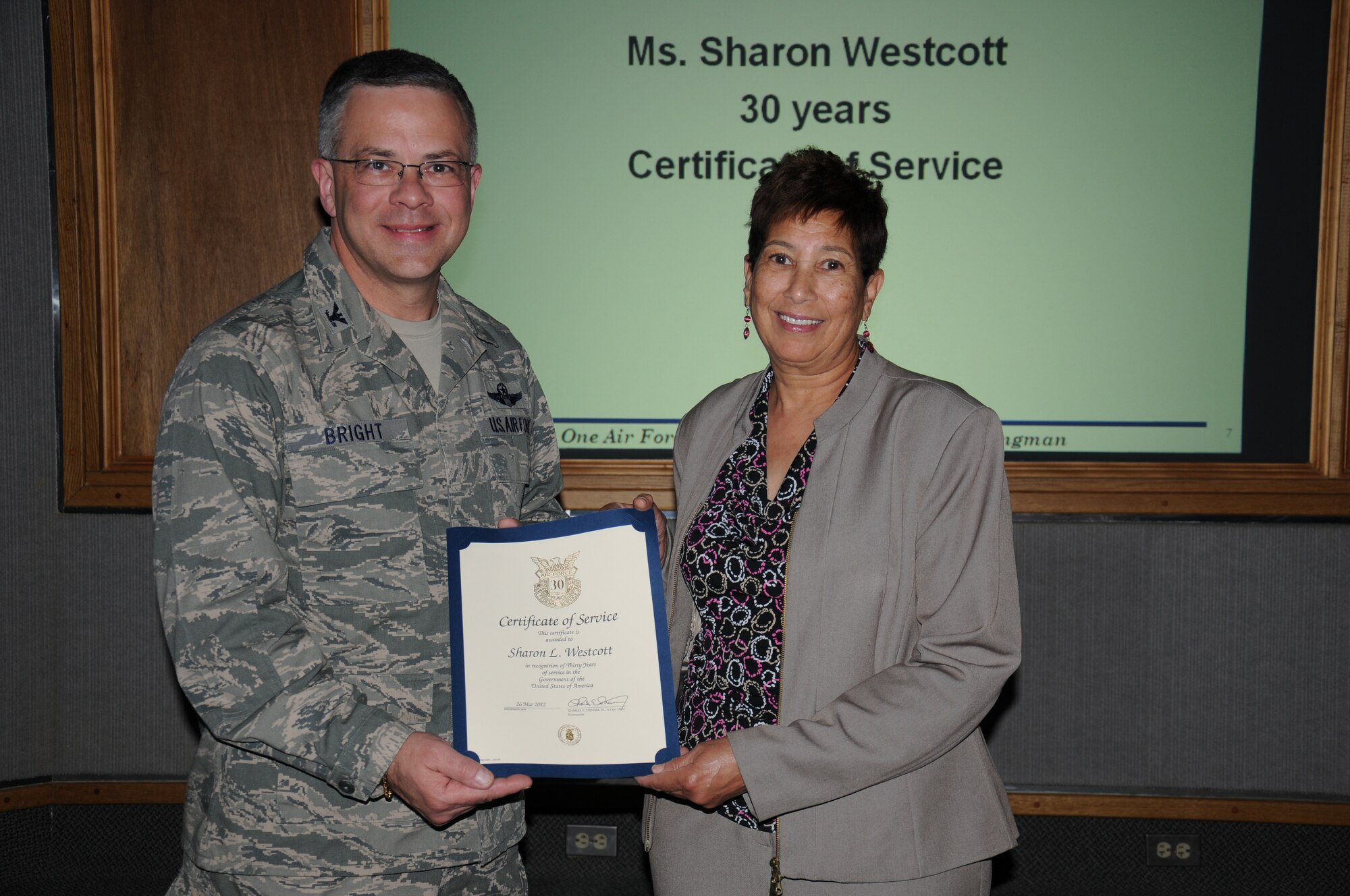 Col. Randal L. Bright, 512th Airlift Wing commander, presents Sharon L. Westcott, 512th Maintenance Group, with a pin and certificate in recognition of her 30 years of civilian service to the Air Force. (U.S. Air Force photo by Capt. Marnee A.C. Losurdo)