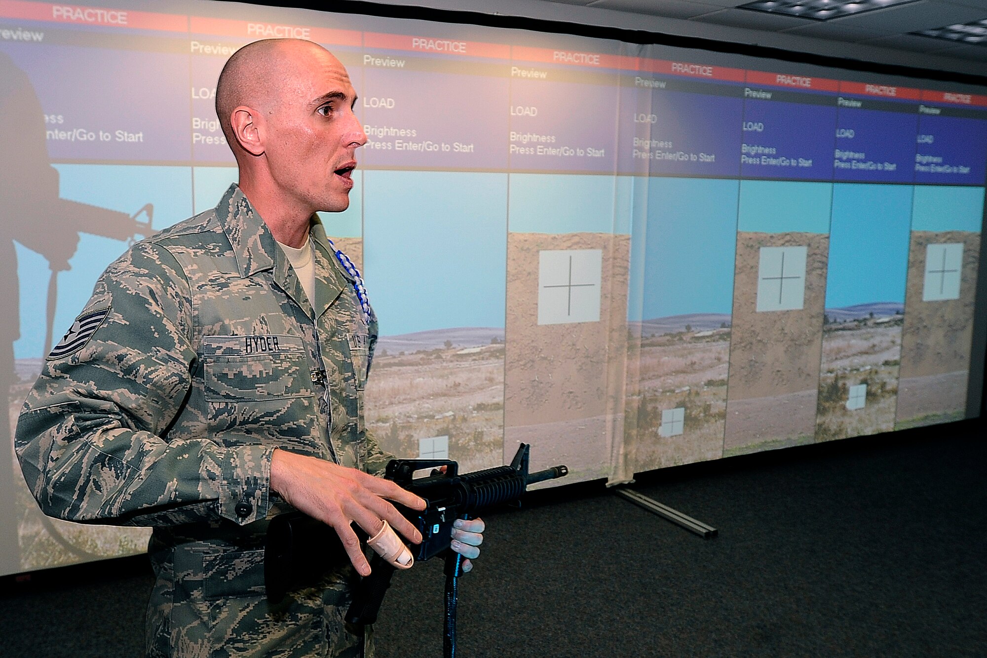 Tech. Sgt. Jon Hyder, an Academy Military Trainer assigned to Cadet Squadron 35, explains how the new firearms training simulator works. (U.S. Air Force Photo/Mike Kaplan)