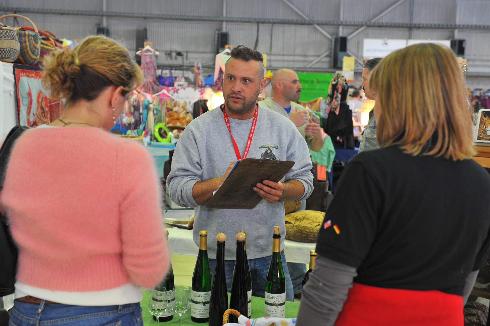 SPANGDAHLEM AIR BASE, Germany – Vito Cipolla, Sailler Cipolla Winery vendor, sells wine to Ann Weggeman, wife of Col. Christopher Weggeman, 52nd Fighter Wing commander, and Kate Julazadeh, wife of Col. David Julazadeh, 52nd Fighter Wing vice commander, at the spring bazaar here March 30. The Spangdahlem Spouses and Enlisted Members Club hosts the bazaar annually allowing vendors from across Europe to share their products with military members and their families. Products include foodstuffs, furniture and traditional German décor. (U.S. Air Force photo/Airman 1st Class Dillon Davis)