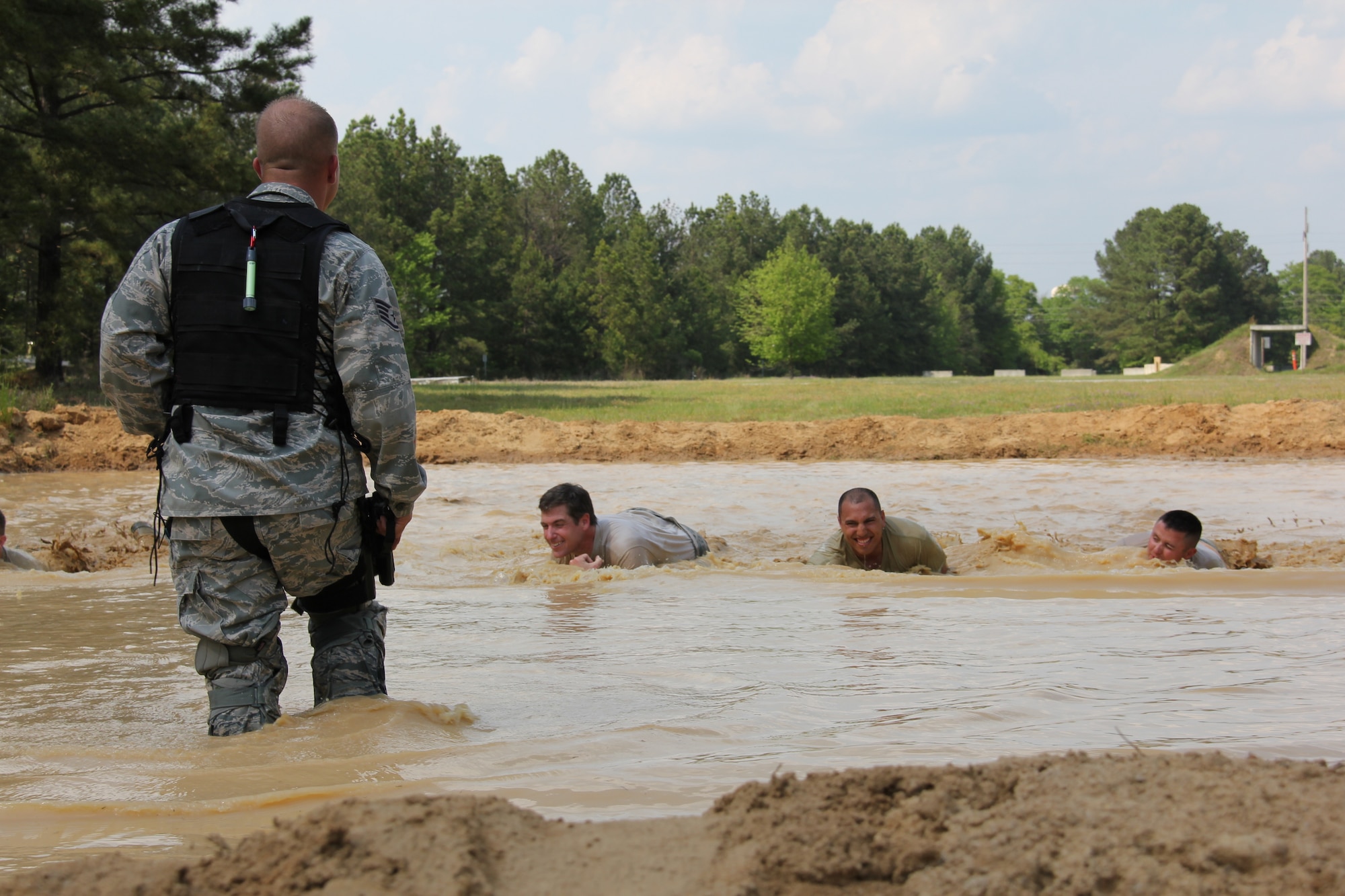 Staff Sgt Till Schanz, 5th Combat Communications Group combat readiness instructor, leads Reynolds Wolf, CNN meteorologist and correspondent, Staff Sgt. Jeffrey Rybold, Tech. Sgt Patricio Escanilla, and  other 5th Combat Communications Group combat readiness instructors in high crawl mud pit tactics here March 28. The three-person CNN team visited the 689th Combat Communications Wing to experience what it is like to be a combat communications Airman for the day. Combat Comm provided hands-on experiences that showcased the physical, technical, and mental readiness of Combat Communicators. (U.S. Air Force photo by Robert Talenti)