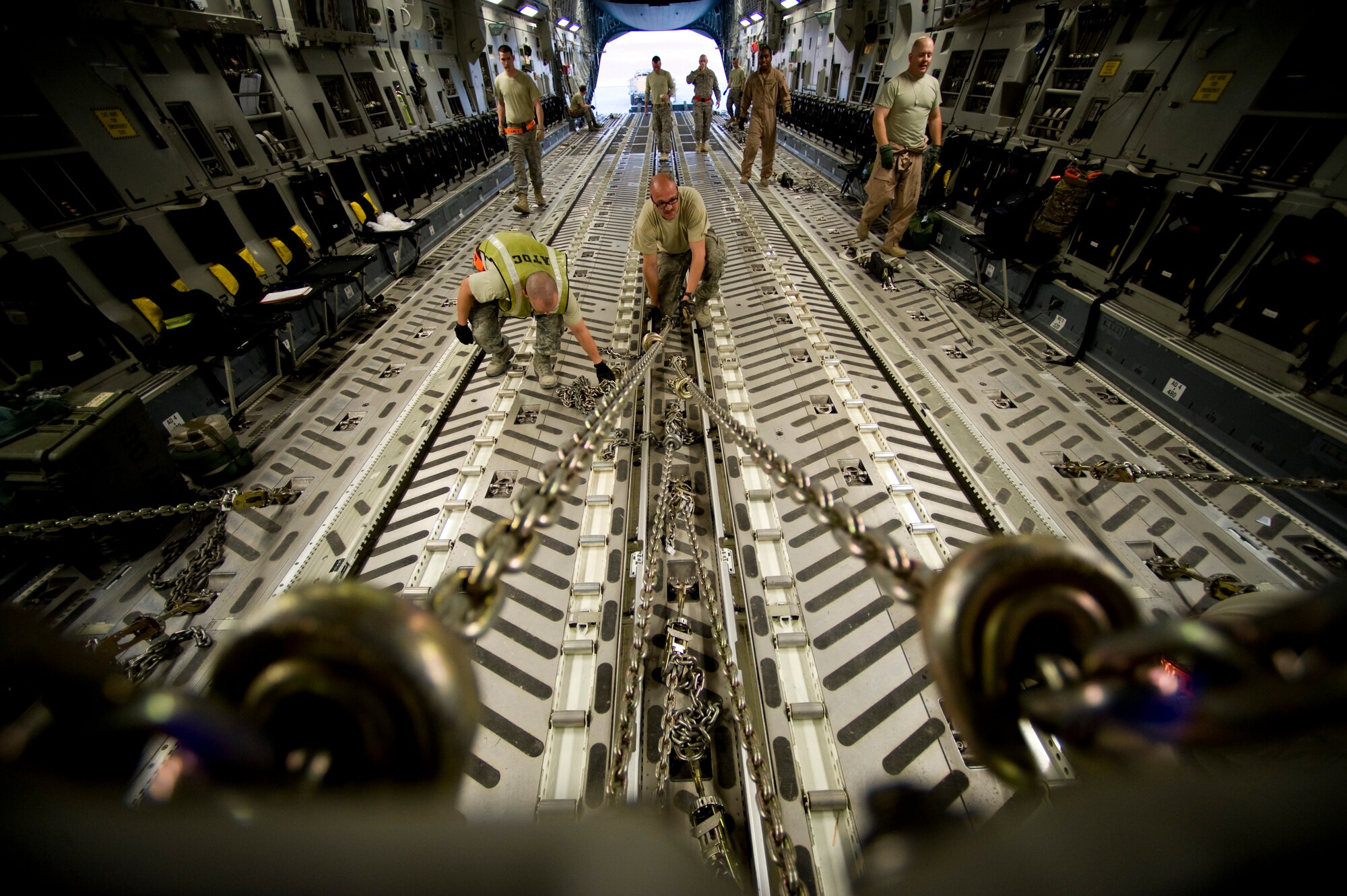 U.S. Air Force Staff Sgt. Emery Woolsey of the 8th Expeditionary Air Mobility Squadron, connects chains to a pallet barrier on a C-17 Globemaster III at an undisclosed location in Southwest Asia, March 28, 2012. The C-17 is one of three aerial resupply platforms utilized by U.S. Air Forces Central's Air Mobility Division. In 2011, the AMD directed the dropping of over 58,000 bundles comprising more than 80 million pounds of critical supplies to personnel in austere combat outposts. (U.S. Air Force photo by Staff Sgt. Greg C. Biondo)