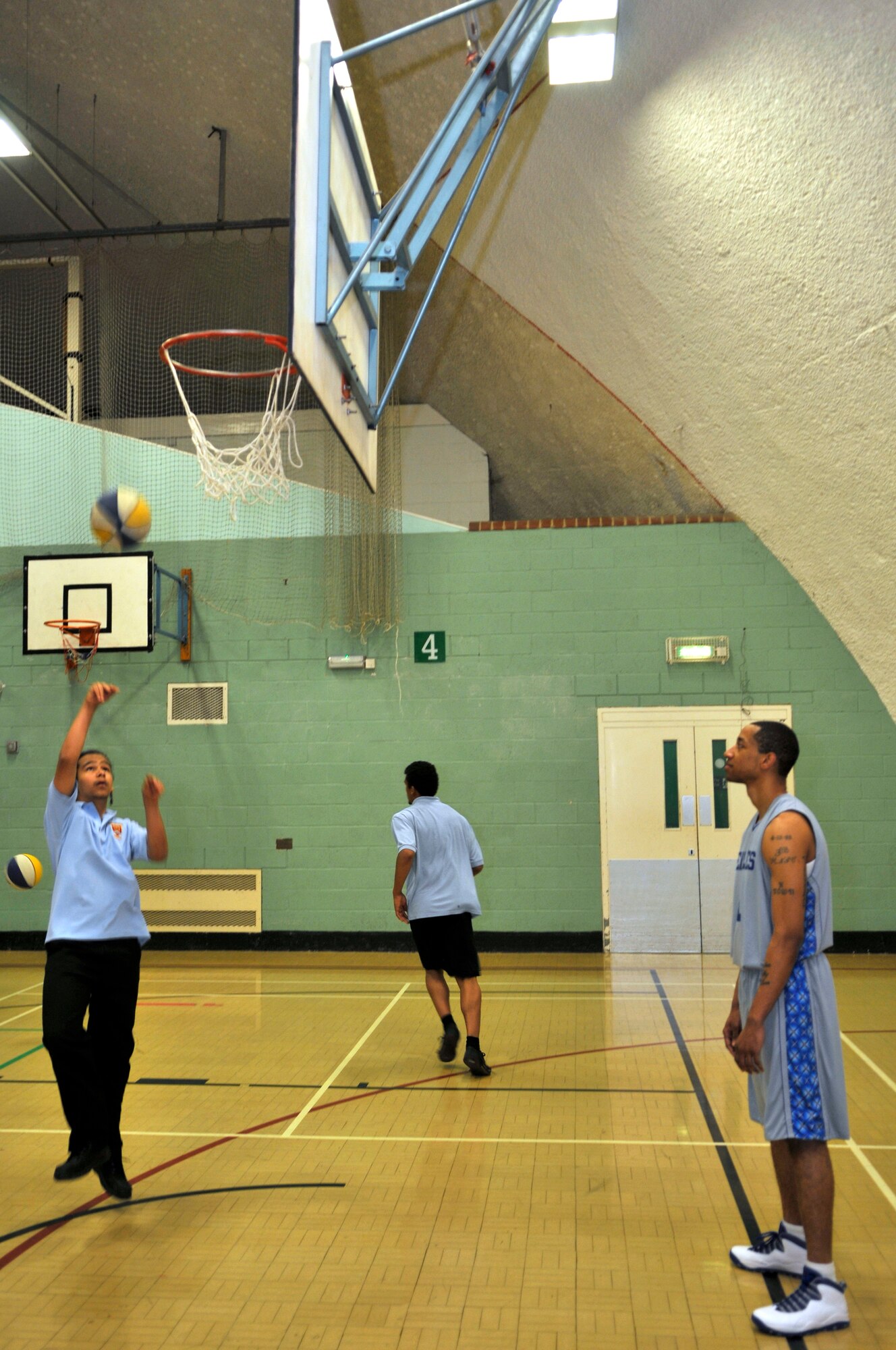 MILDENHALL, England - Donovan Stamsbury shoots a layup as Tech. Sgt. Jarrod Butler, 48th Fighter Wing command post NCO in charge of transportation, watches during a visit to Mildenhall College of Technology March 28, 2012. Butler and other members of the Royal Air Force Lakenheath Eagles varsity basketball team came to the school to mentor the pupils and run basketball drills. (U.S. Air Force photo by Staff Sgt. David Dobrydney)