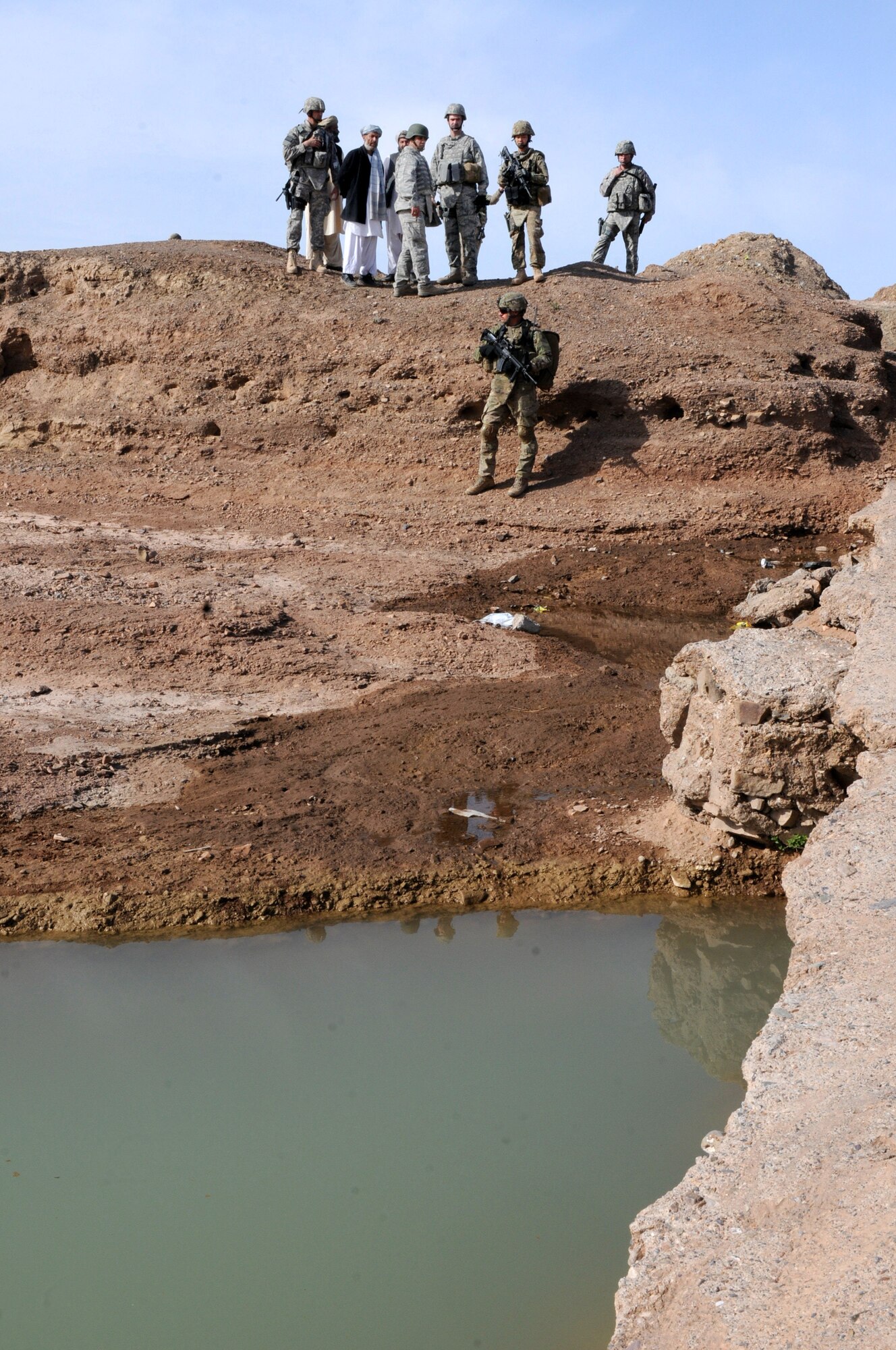 Advisors with the 838th Air Expeditionary Advisory Group assess a spillway that delivers water to multiple villages during a humanitarian site survey, Shindand Air Base, Afghanistan, March 22, 2012. The advisors? focus is the rerouting of flood water that is causing damage to various aqueduct systems and repair of a collapsed karez, a water supply system that feeds the villagers, live stock and crops of the Moghalan-e-now and Moghalan-khona villages located directly outside Shindand AB. (U.S. Air Force by Staff Sgt. Nadine Y. Barclay)
