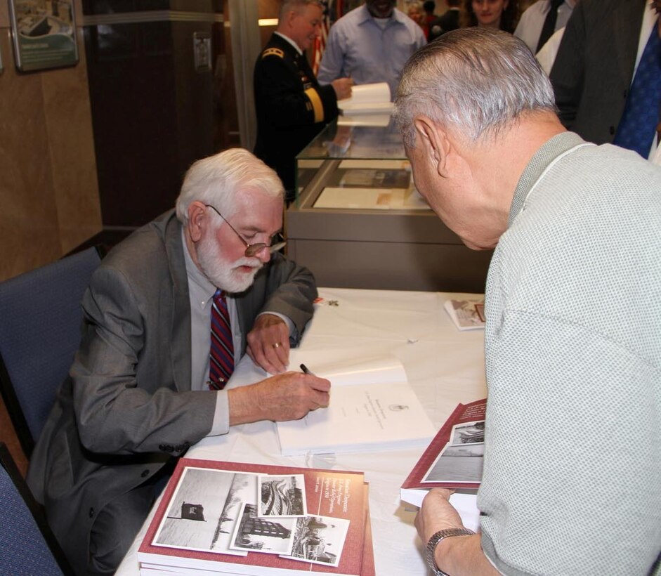 Leland Johnson signs a copy of his book “Situation Desperate: U.S. Army Corps of Engineers Disaster Relief Operations, Origins to 1950”.  Johnson is a freelance writer and researcher from Westmoreland, Tenn.  The Office of History officially published the book in a ceremony March 23 at U.S. Army Corps of Engineers Headquarters in Washington, D.C.  (Photo by John Hoffman, USACE Headquarters)