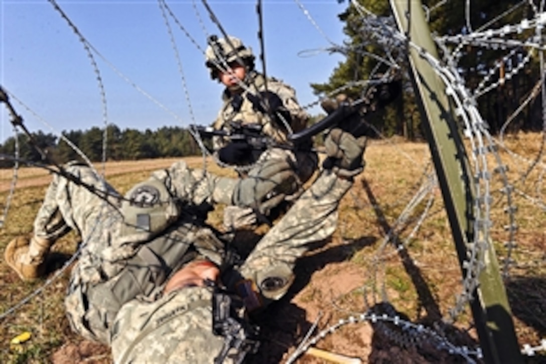 Two U.S. Army soldiers breach a wire obstacle during a situational training exercise on Grafenwoehr Training Area, Germany, March 22, 2012. The soldiers are assigned to the 3rd Squadron, 2nd Cavalry Regiment.