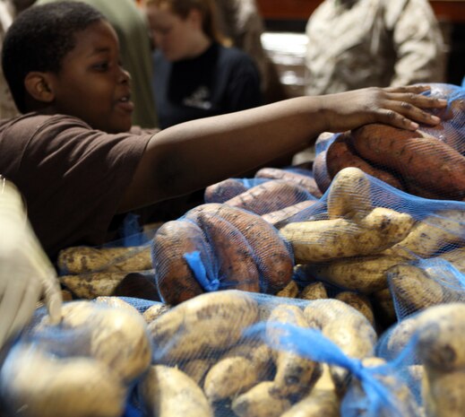 A volunteer adds a bag of sweet potatoes to the pile at the Food Bank of Central and Eastern North Carolina in Greenville, N.C., March 31, 2012. The children from local volunteer centers teamed up with Marines from 2nd Maintenance Battalion, 2nd Marine Logistics Group to tackle some large projects like bagging sweet potatoes for distribution and sorting through multiple pallets of food within the warehouse.