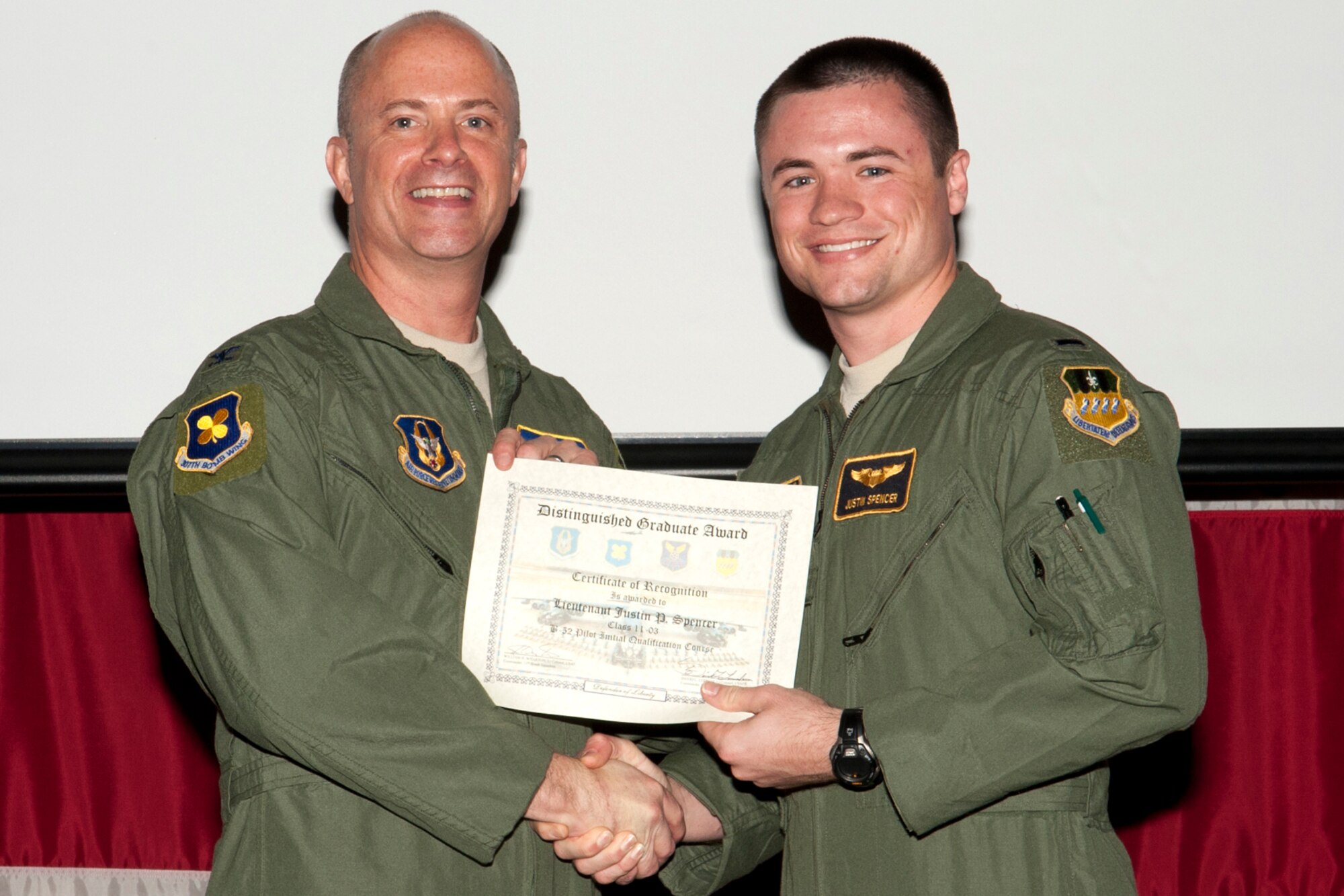 U.S. Air Force Col. Jon Ellis, 307th Bomb Wing commander, presents a Distinguished Graduate certificate to 1st Lt. Justin Spencer during the Formal Training Unit Class 11-03 graduation ceremony on Barksdale Air Force Base, La., March 30, 2012. Spencer, a Copilot graduate, demonstrated at least a 90 percent average in all areas of training and performed consistently and clearly above his peers. (U.S. Air Force photo by Master Sgt. Greg Steele/Released)
