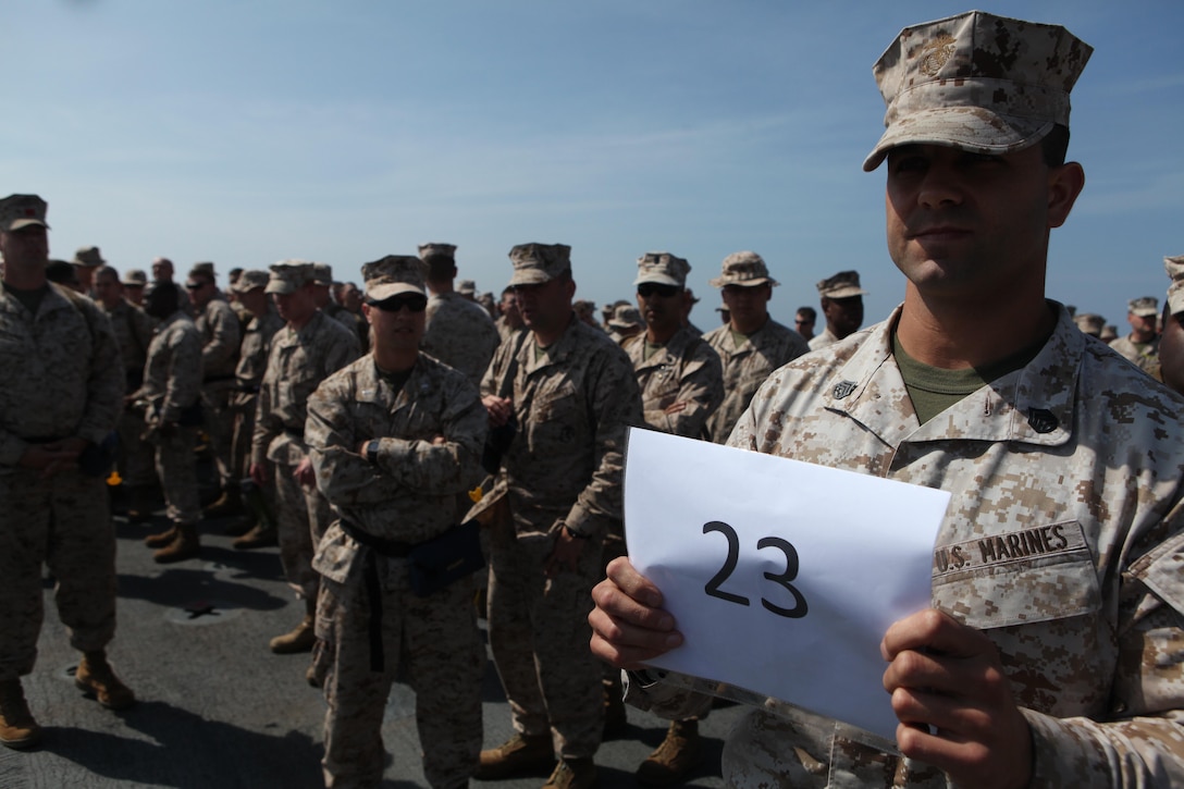 Staff Sgt. Jeffrey Perry, the motor transportation chief with Combat Logistics Battalion 24, 24th Marine Expeditionary Unit, holds up a sign to help guide Marines and Sailors to their life boat during an abandon ship drill on the flight deck of the USS Gunston Hall, March 31. Marines and Sailors aboard the ship conducted the drill as a way to become familiarized with the egress plan in the event they suddenly need to abandon the ship.