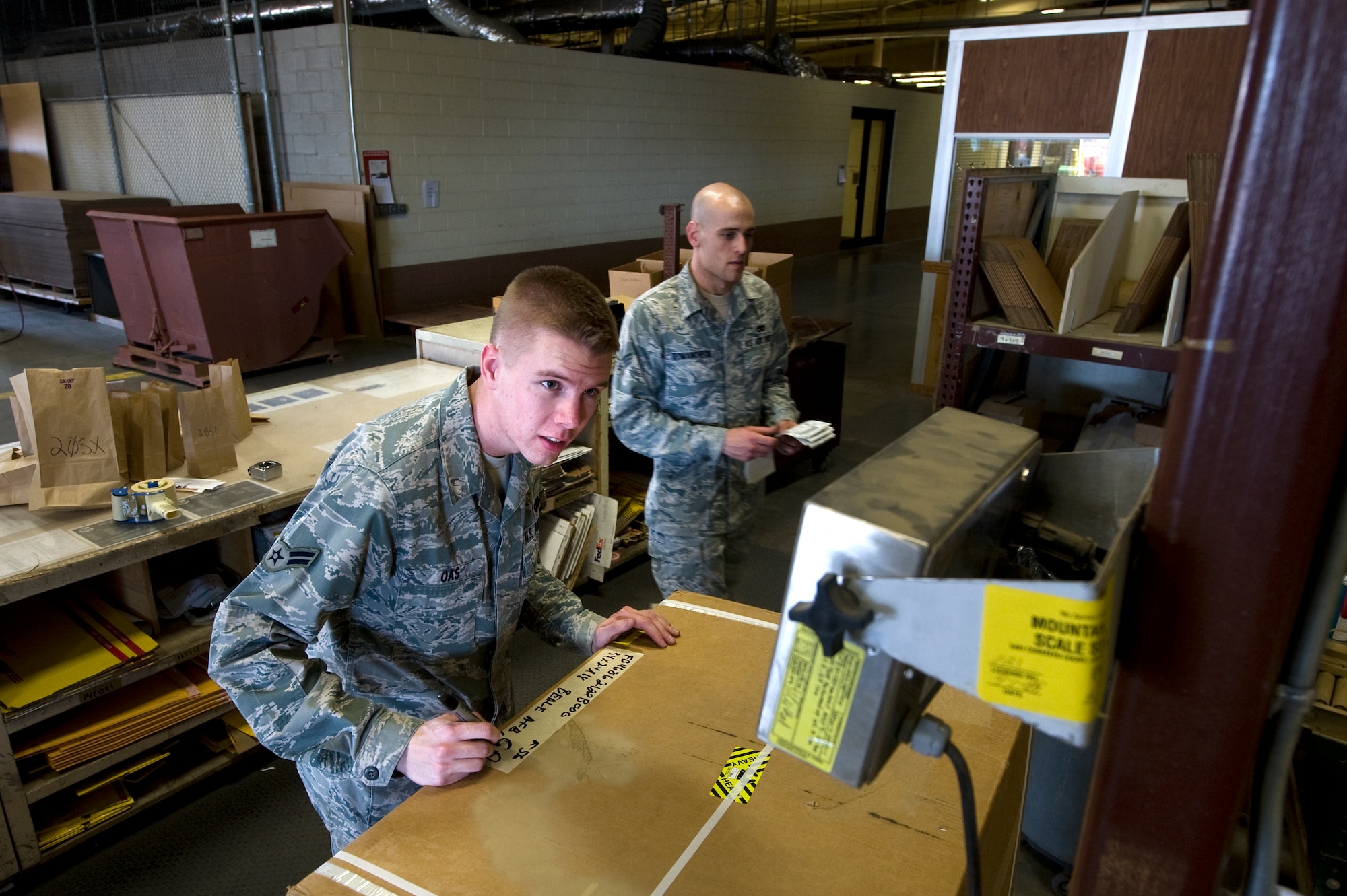 U.S. Air Force Airman 1st Class Alexander Oas (left), 99th Logistics Readiness Squadron traffic management journeyman, weighs a piece of cargo on a scale as Senior Airman Steven Romancheck (right), 99th Logistics Readiness Squadron traffic management journeyman, prepares to label cargo May 1, 2012, at Nellis Air Force Base, Nev. The 99th LRS is responsible for moving cargo 24 hours a day with 100 percent accountability of assets. (U.S. Air Force photo by Staff Sgt. Christopher Hubenthal)
