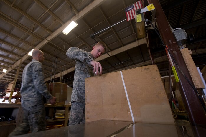 U.S. Air Force Airman 1st Class Alexander Oas (right), 99th Logistics Readiness Squadron traffic management journeyman, applies a label to a piece of cargo as Senior Airman Steven Romancheck (left), 99th Logistics Readiness Squadron traffic management journeyman, moves another piece of cargo May 1, 2012, at Nellis Air Force Base, Nev. The 99th LRS transports approximately 1200 pieces of cargo a month. (U.S. Air Force photo by Staff Sgt. Christopher Hubenthal)