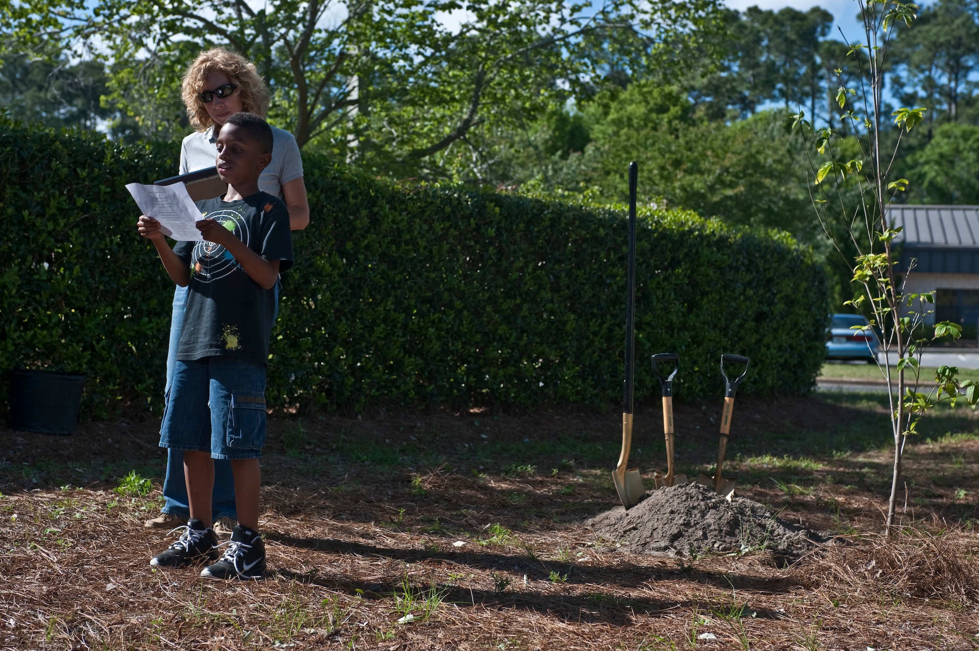 Kristal Walsh, an environmental specialist from the 1st Special Operations Civil Engineering Squadron, stands by as Jazir Simon, a Youth Center student, reads a poem at a stream by the Child Development Center Main, Hurlburt Field, Fla., April 26, 2012. The poem, written by Susan M. Paprocki, was about the benefits of trees and encouraging children to love them. (U.S. Air Force Photo/Airman 1st Class Hayden K. Hyatt)
