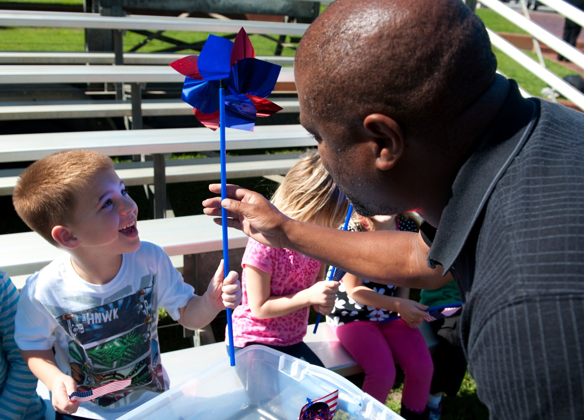 A child from the Child Development Center receives an American flag and pinwheel from Gary Scott, a Family Advocacy Program assistant from 1st Special Operations Medical Operations Squadron, during a proclamation-signing ceremony at the Airpark on Hurlburt Field, Fla. April 24, 2012. Children at the event held American flags to commemorate being a military child and pinwheels as part of the National Blue Ribbon campaign to prevent child abuse. (U.S. Air Force photo by Airman 1st Class Christopher Williams) (RELEASED)