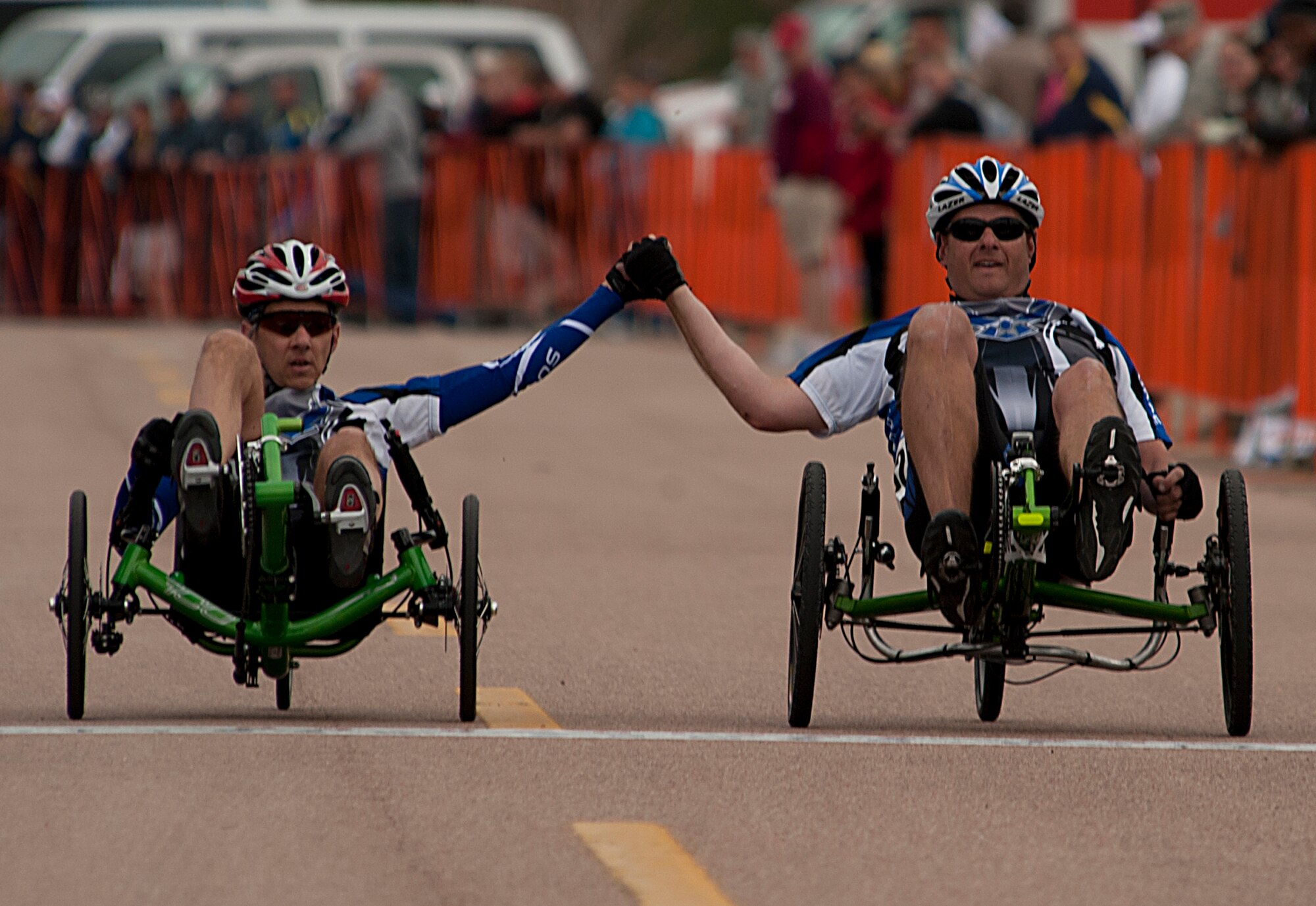 U.S. Air Force Senior Master Sgt. Mike Sanders, left, and Maj. Scott Bullis hold hands as they cross the finish line as they take part in the recumbent cycling event of Warrior Games 2012 at the U.S. Air Force Academy in Colorado Springs, Colo., May 1, 2012. (U.S. Air Force photo by Val Gempis/Released)