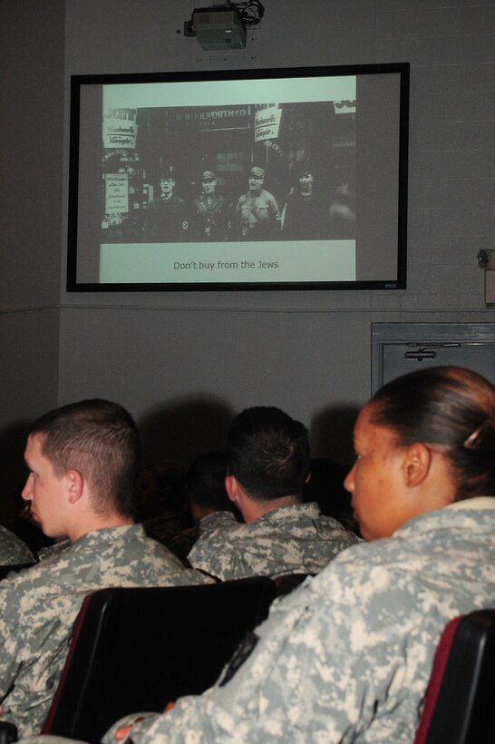 The audience views holocaust photos in a slideshow during the Days of Remembrance Ceremony at Fort Eustis, April 24, 2012. The photos displayed historical data to show where Ipson, holocaust survivor, and his family began their journey, and where they all, except his mother, father and sister, died. (U.S. Air Force photo by Staff Sgt. Ashley Hawkins/Released)