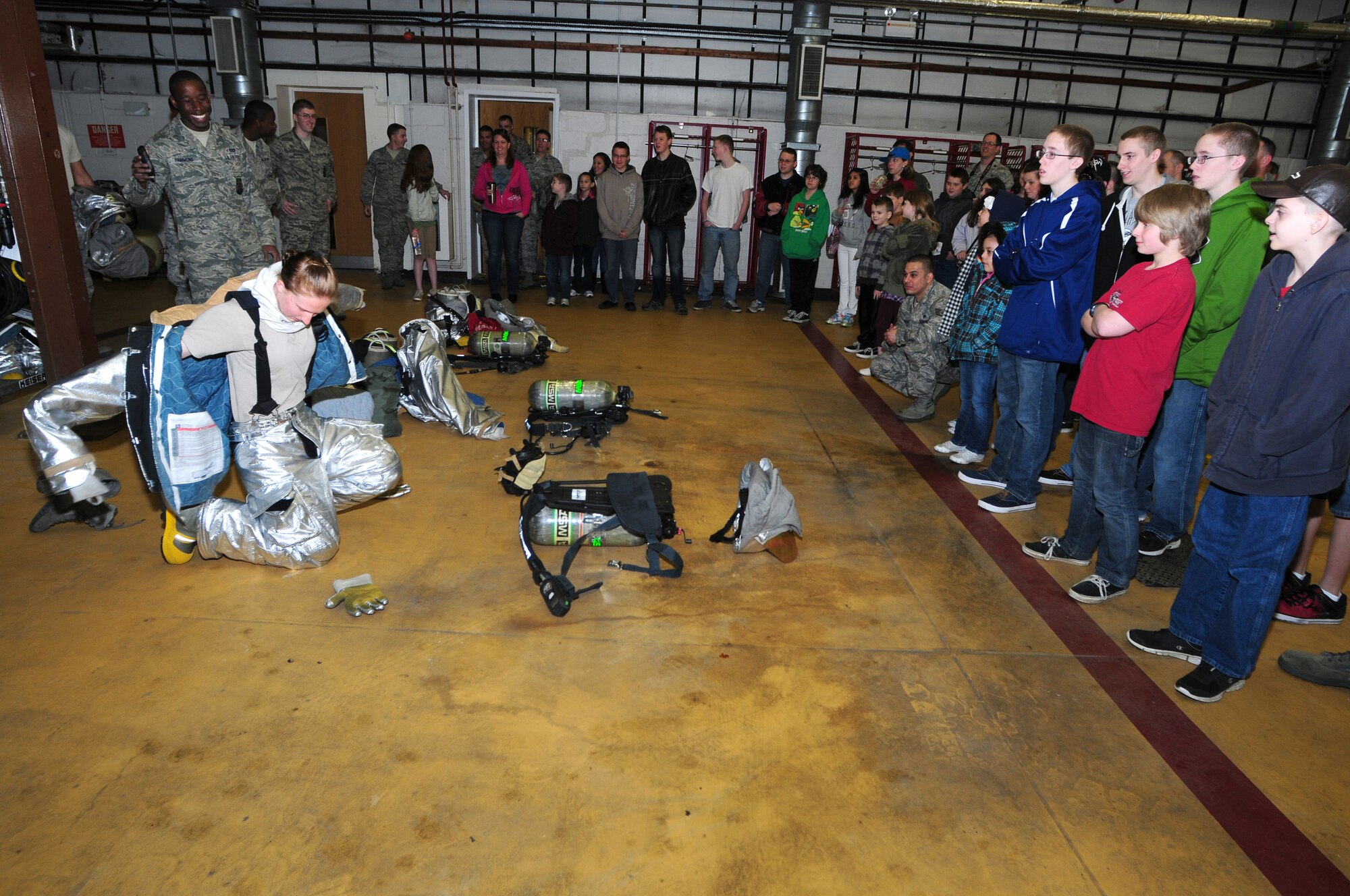 ROYAL AIR FORCE LAKENHEATH, England -- Airman 1st Class Ashley Eisenbarth, 48th Civil Engineer Squadron firefighter, demonstrates to students how she dons her gear while Senior Airman Cordarrell Hammond, 48th CES crew chief times her at the fire department during Job Shadow Day April 27, 2012.  Firefighters must don their gear in two minutes or less. Job Shadow Day provided children the opportunity to see and learn about different Air Force jobs and allowed hands-on experience in an interactive environment. (U.S. Air Force photo by Senior Airman Tiffany M. Deuel)