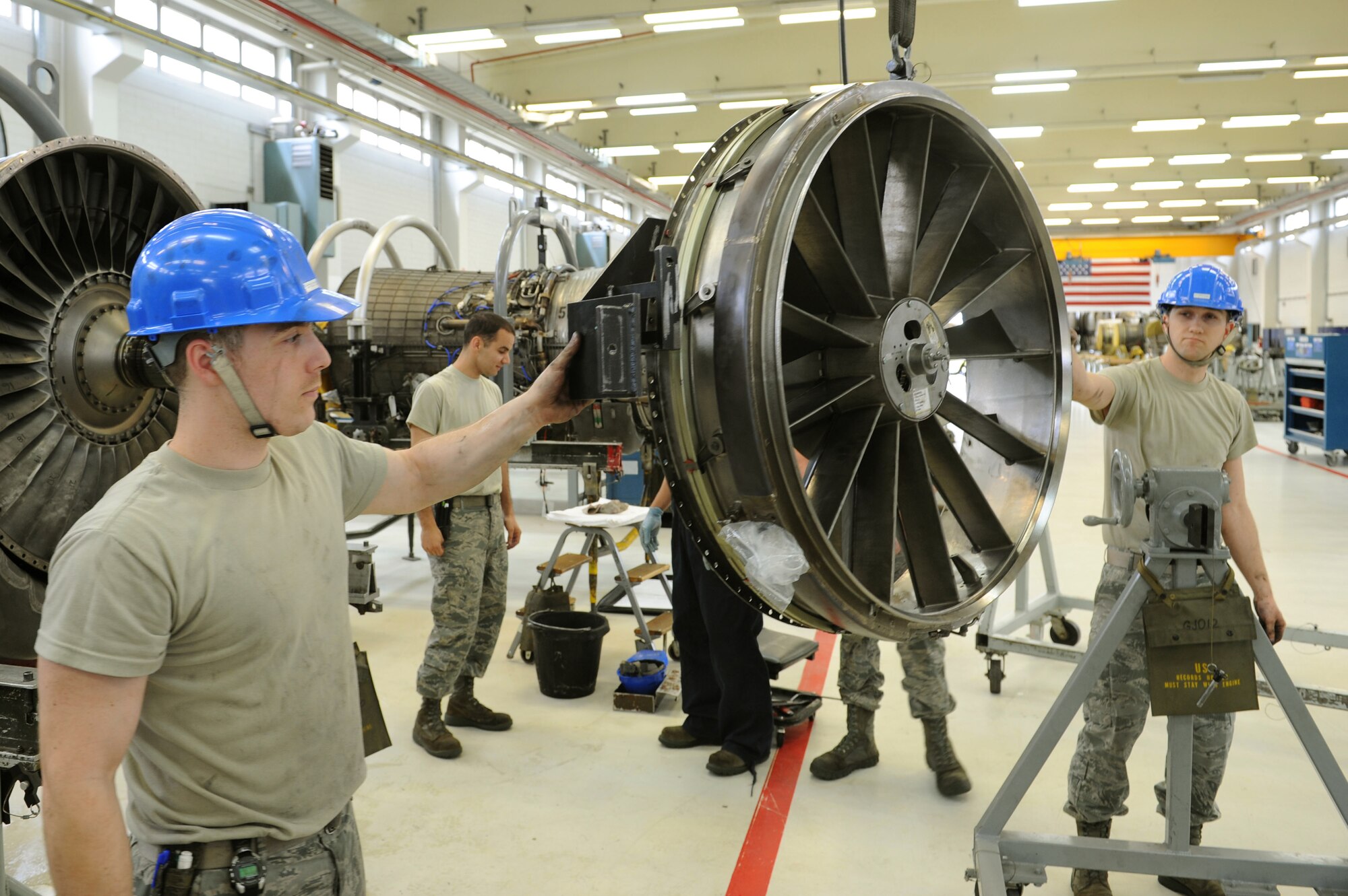 SPANGDAHLEM AIR BASE, Germany – Senior Airman Willis Jenson, left, and Senior Airman Braden Duke, 52nd Component Maintenance Squadron aerospace propulsion technicians, guide the front frame from of F-16 Fighting Falcon turbine to a disassembly stand during the removal of all moving parts of the engine at Bldg. 73 here April 30. Technicians replace these moving parts in a turbine every 4,000 flight hours as required by the service life extension program. CMS provides maintenance support to the 52nd Fighter Wing, the 31st FW at Aviano AB, Italy, and all U.S. F-16 units powered by F-110 engines in the European theater and deployed locations. (U.S. Air Force photo by Senior Airman Christopher Toon/Released)
