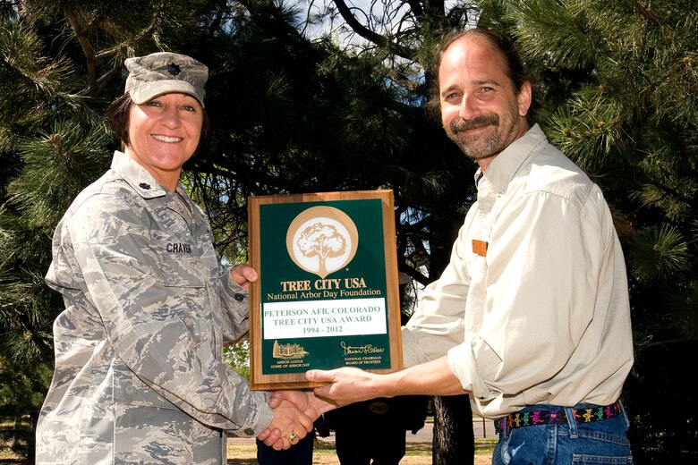 Lt. Col. Kathy Craver, 21st Mission Support Group deputy commander, receives the Tree City U.S.A. Award from Andy Schlosberg, a forester with the Colorado State Forest Service, during the National Arbor Day observance April 26 at the R.P. Youth Center Facility. This was the 18th consecutive year Peterson AFB has received the award. (U.S. Air Force photo/Dennis Howk)