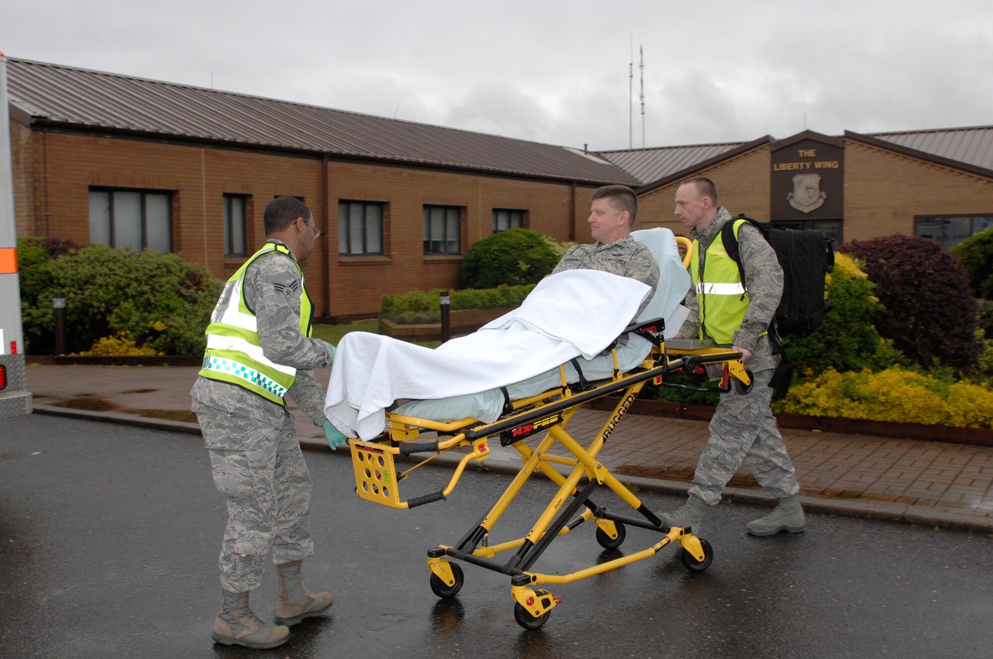 ROYAL AIR FORCE LAKENHEATH, England -- Senior Airman Errington Neysmith and Tech. Sgt. Derrick Rutherford, 48th Medical Operations Squadron first responders, rush Col. Kyle Robinson, 48th Fighter Wing commander, to an awaiting ambulance April 25, 2012. The 48th Medical Group enacted a creative initiative to give the wing’s new commander insight into their operations. As part of the simulation Robinson felt ‘abdominal pains’ following a working lunch with Chief Master Sgt. SaRita Lathan, 48th Fighter Wing command chief, and when the pains worsened she dialed 911. (U.S. Air Force photo by Tech. Sgt. Lee A. Osberry Jr.)