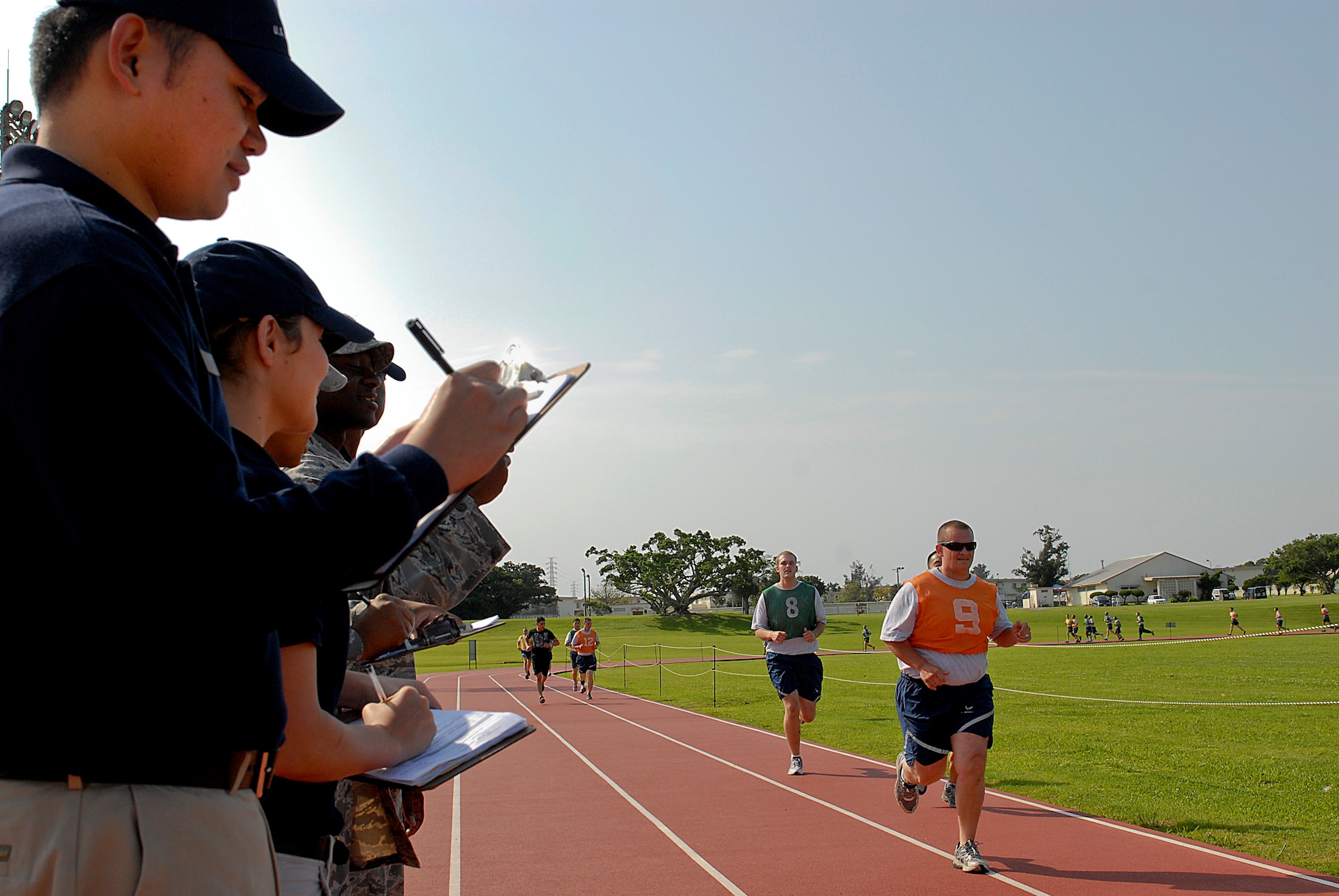 Kadena Fitness Assessment Cell members watch as Airmen run a mile and a half during their physical fitness assessment at Kadena Air Base, Japan, April 27, 2012. Unit physical training leaders started a new augmentation schedule today to help the Fitness Assessment Cell administer Air Force fitness tests. (U.S. Air Force photo/ Airman 1st Class Malia Jenkins)