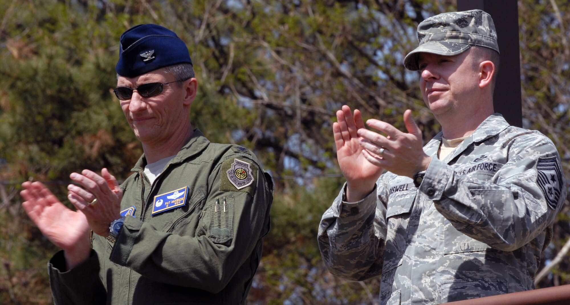 Col. Patrick McKenzie, 51st Fighter Wing commander, and Chief Master Sgt. Brendan Criswell, 51st FW command chief, applaud passing grades announced April 30, 2012, during the outbrief to the Pacific Air Forces Consolidated Unit Inspection.  The wing was the first PACAF wing to undergo a CUI, which combined several inspections into one.  (U.S. Air Force photo / Senior Master Sgt. Stuart Camp)