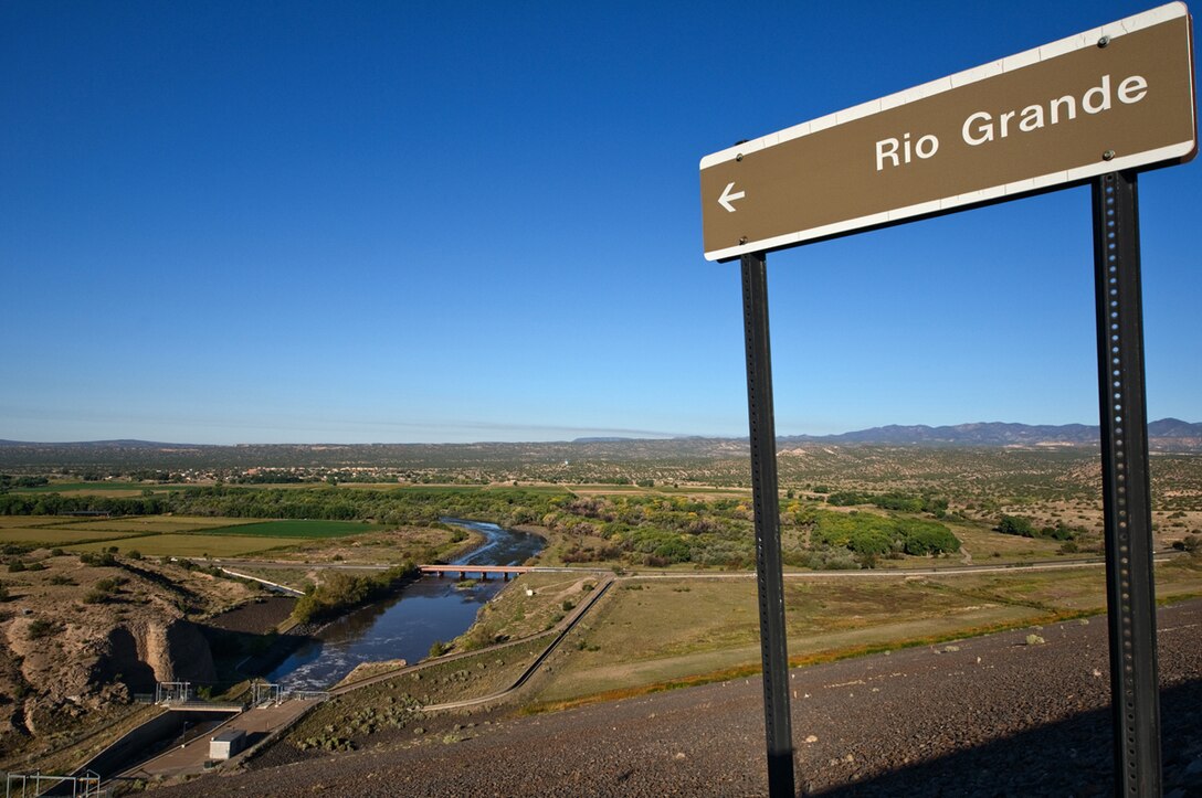 A sign stands atop the Cochiti Lake Dam that points to the Rio Grande below. 