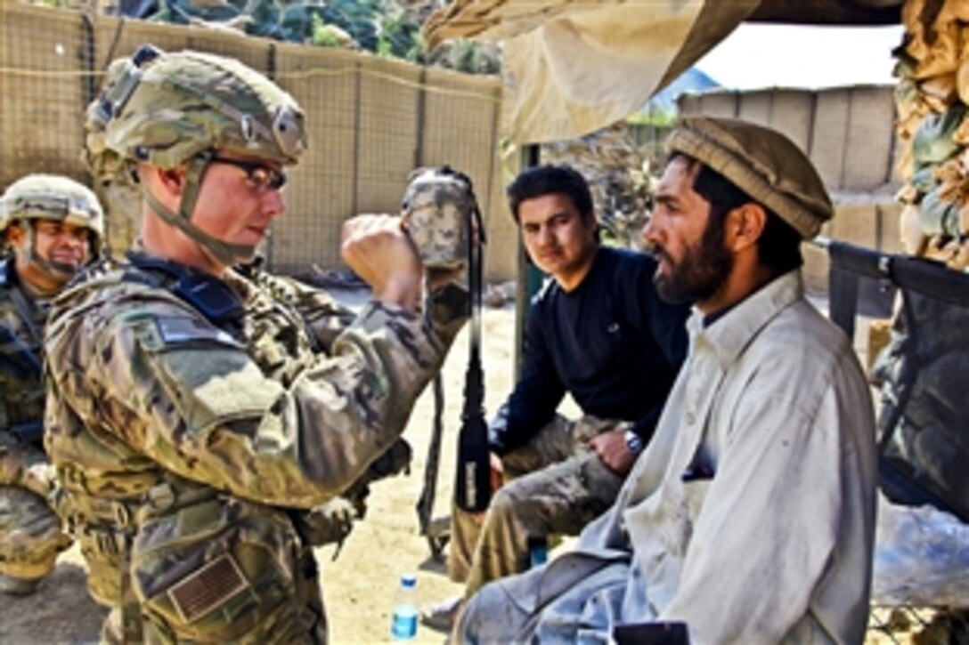 U.S. Army Staff Sgt. Ryan Markle uses a handheld identity detection device on an Afghan man on Contingency Operating Post Pirtle King in Afghanistan's Kunar province, April 18, 2012. 